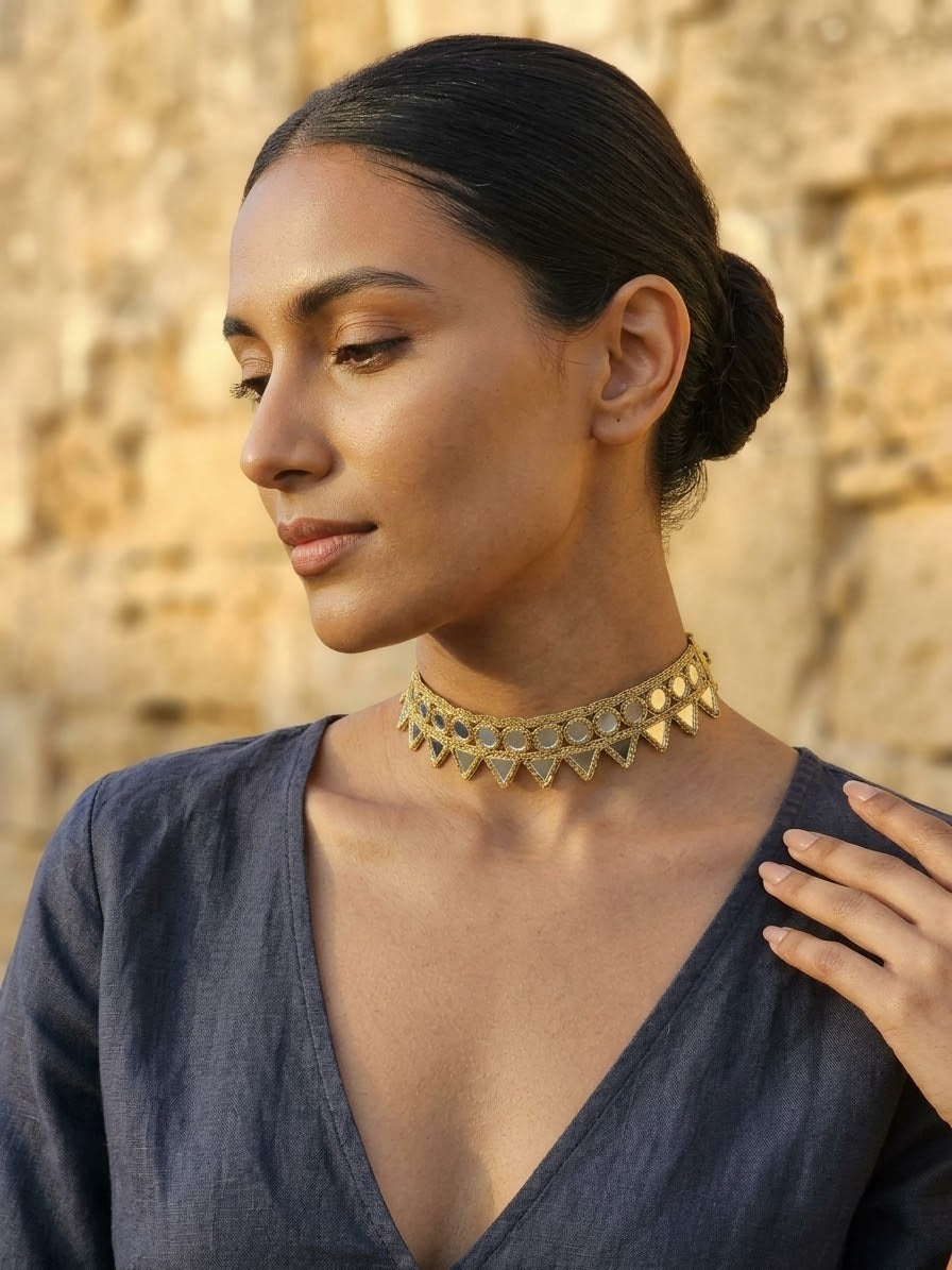 Collar choker dorado con pedrería azul y puntas pequeñas en el contorno del cuello