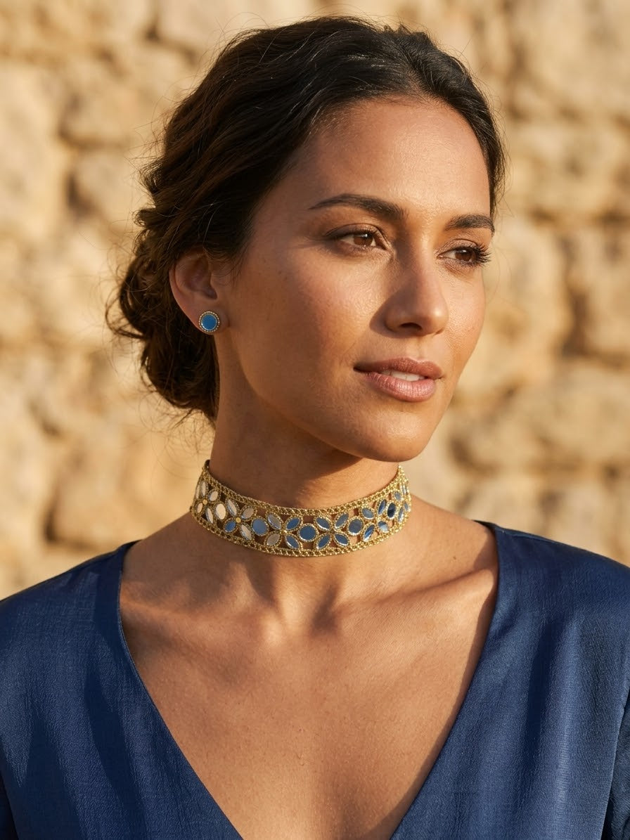 Collar tipo choker dorado con pedrería azul en el cuello, con vestido azul