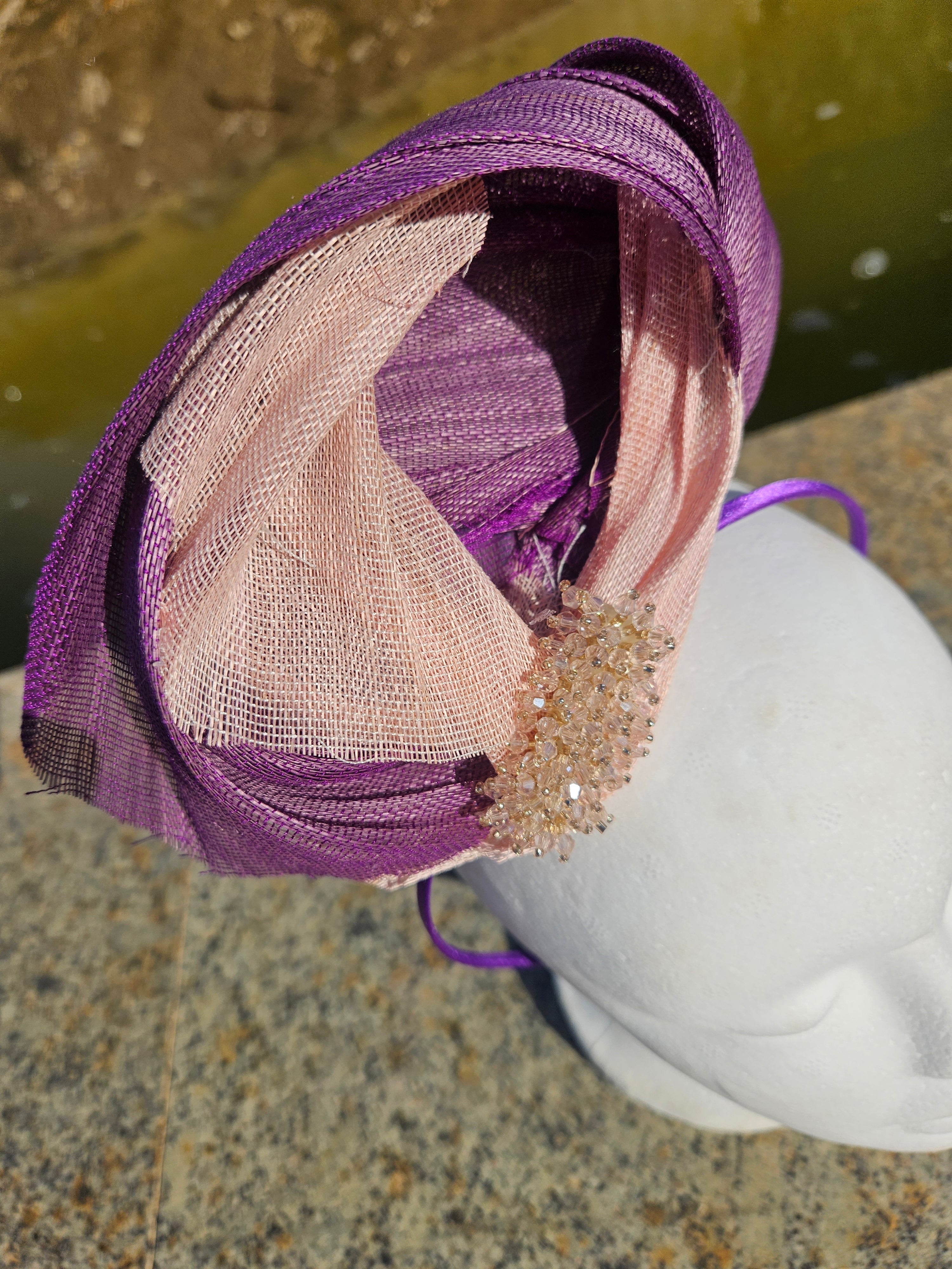 Tocado morado con malla beige traslúcida y adorno dorado tipo flor en primer plano