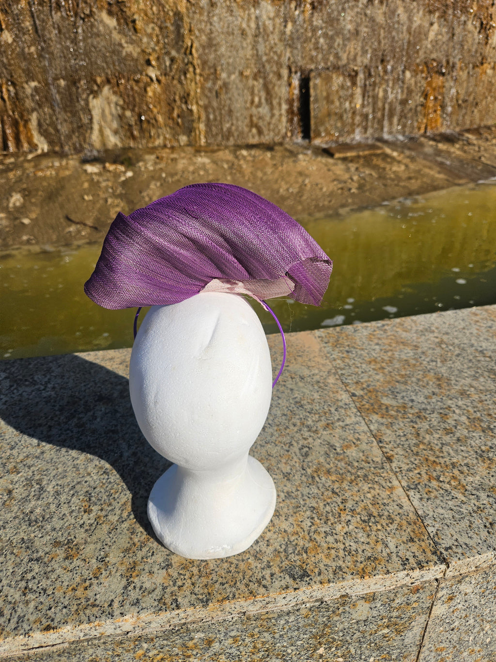Tocado morado drapeado estilo fascinator sobre la cabeza, con malla beige y adorno dorado