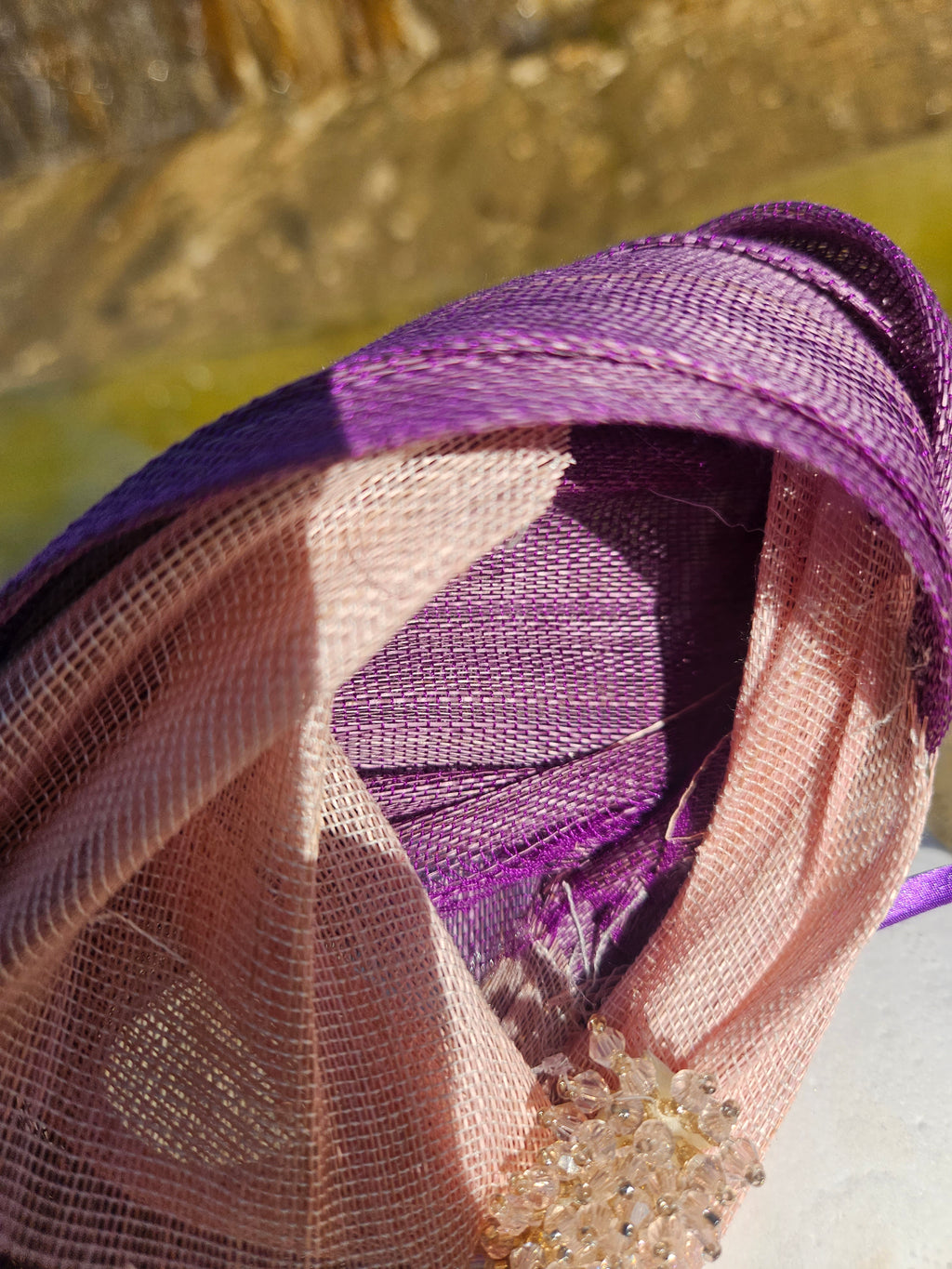 Tocado morado con malla beige y adorno dorado en detalle, con interior visible