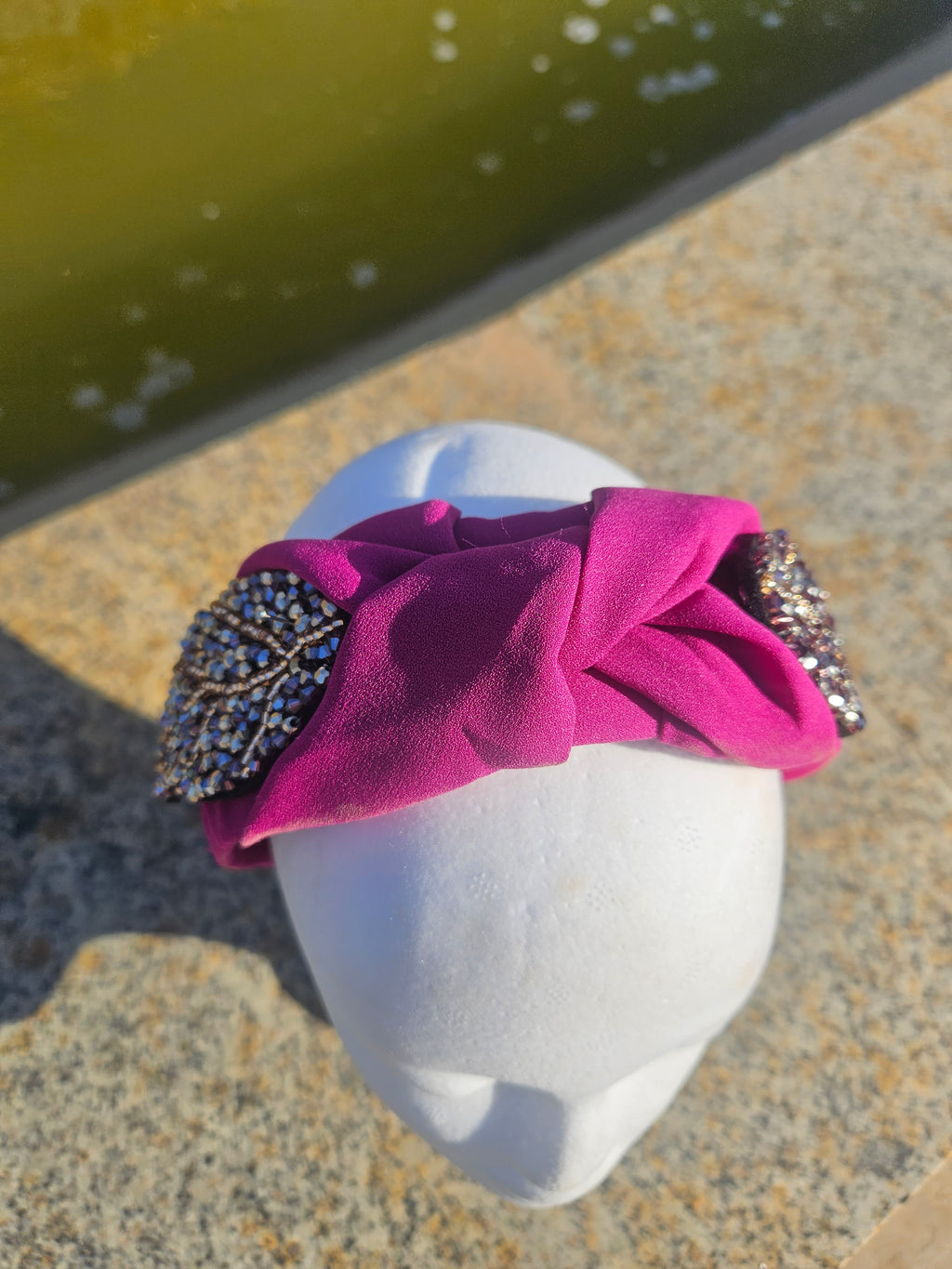 Diadema fucsia con lazo y pedrería oval negra sobre el frontal