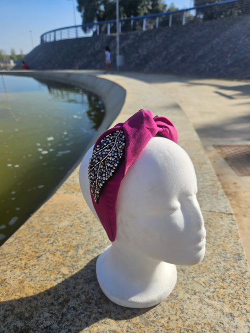 Diadema fucsia con lazo y adorno oval negro de pedrería brillante