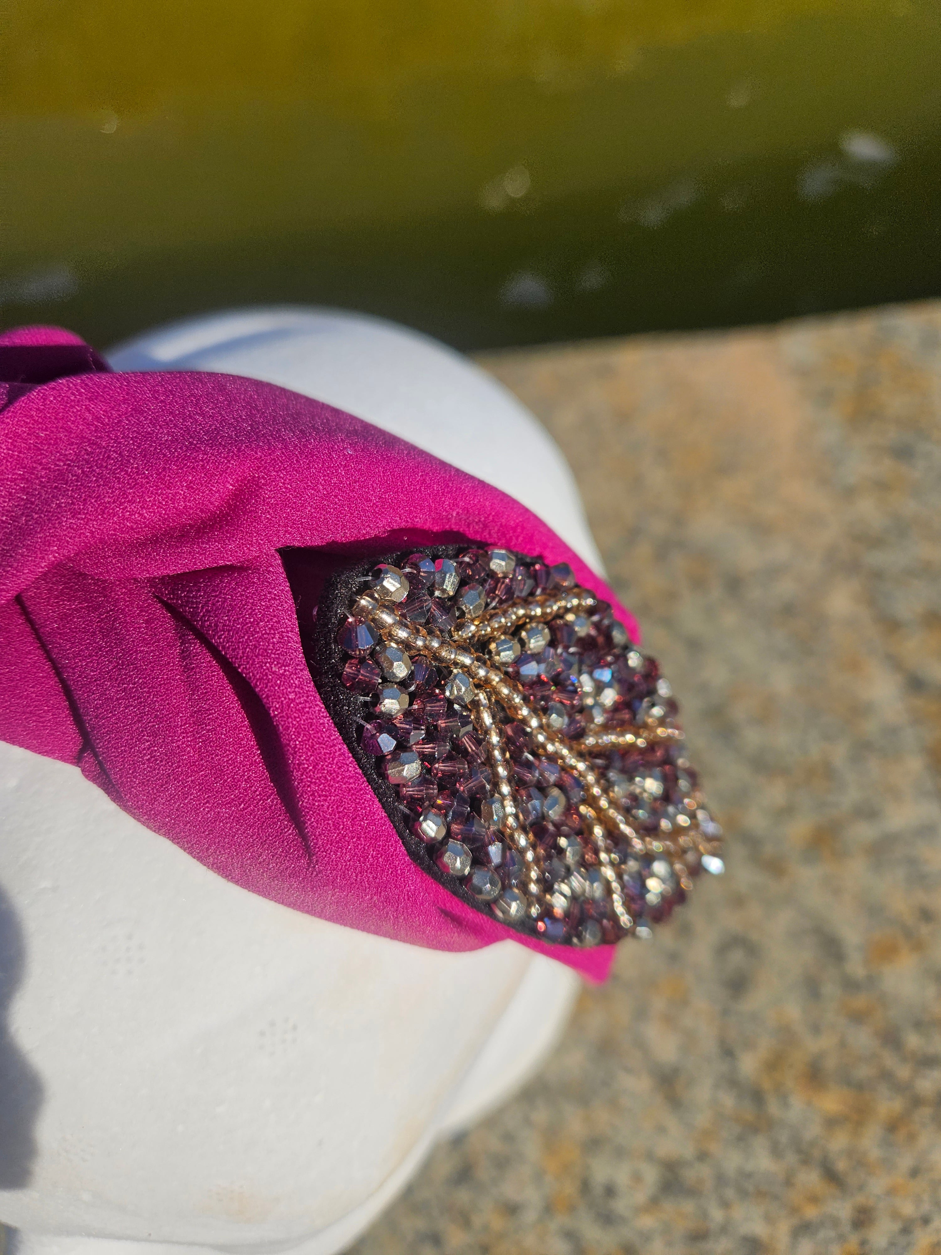 Diadema fucsia con pedrería oval negra y detalles metálicos brillantes