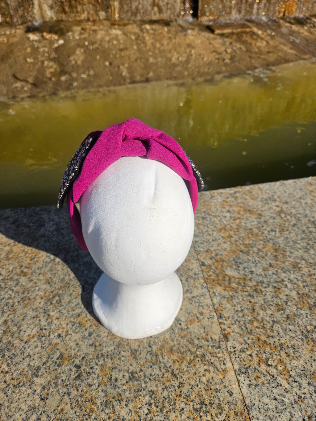 Diadema con lazo fucsia y adorno oval negro de pedrería, vista frontal