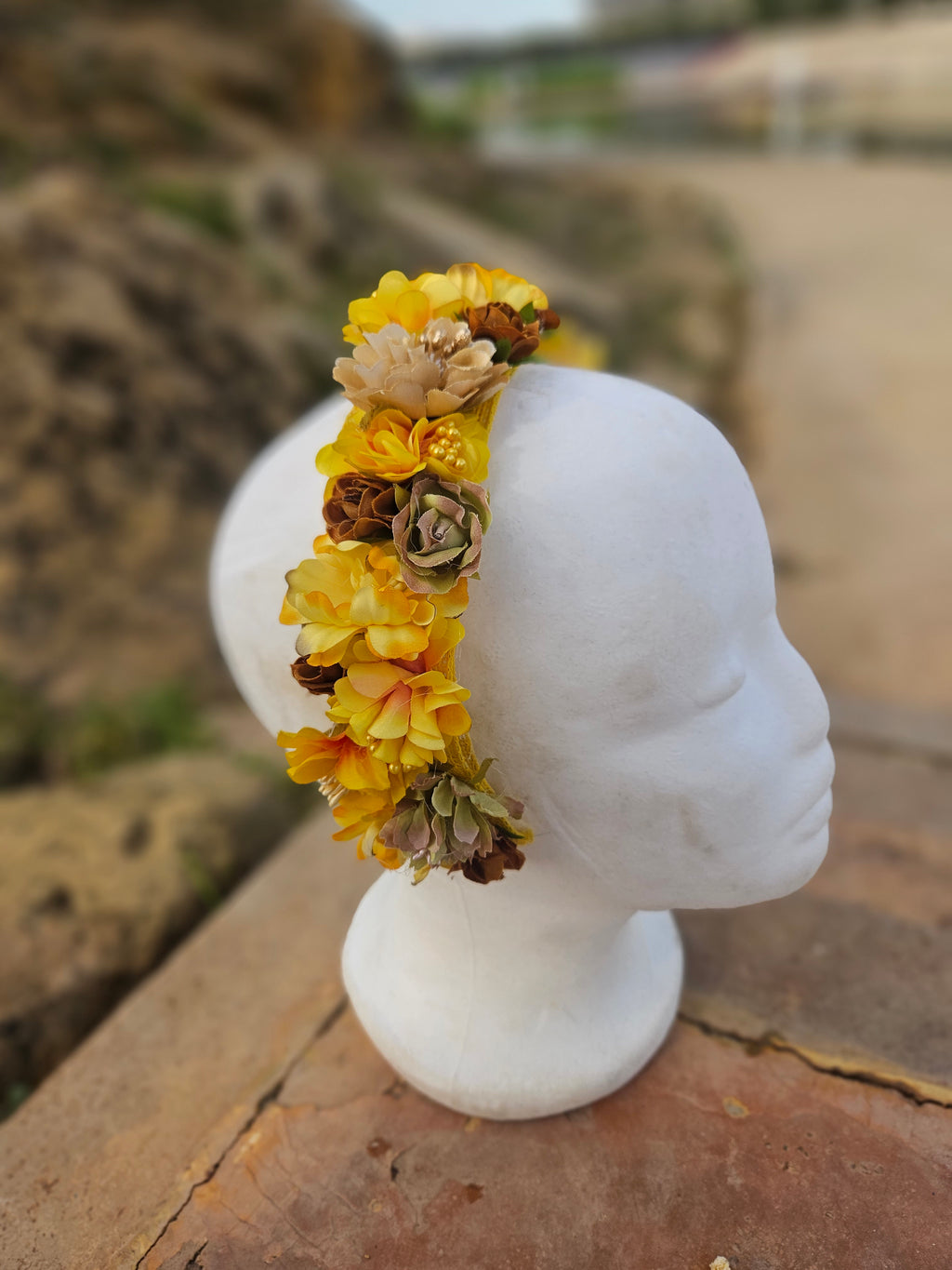Diadema floral amarilla, flores en tonos beige y marrón, vista lateral sobre maniquí