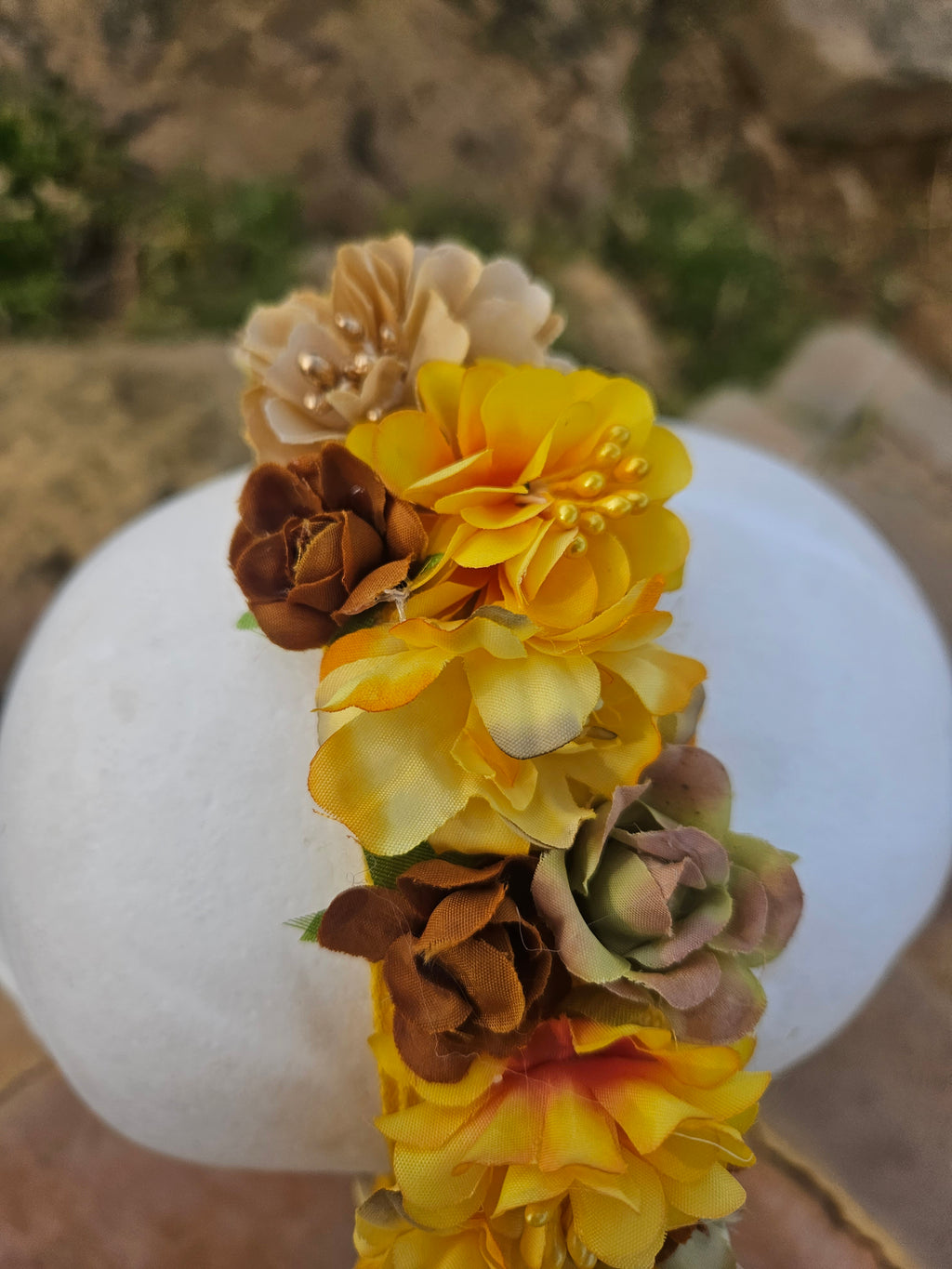 Diadema floral amarilla y marrón con flores grandes, vista frontal cercana
