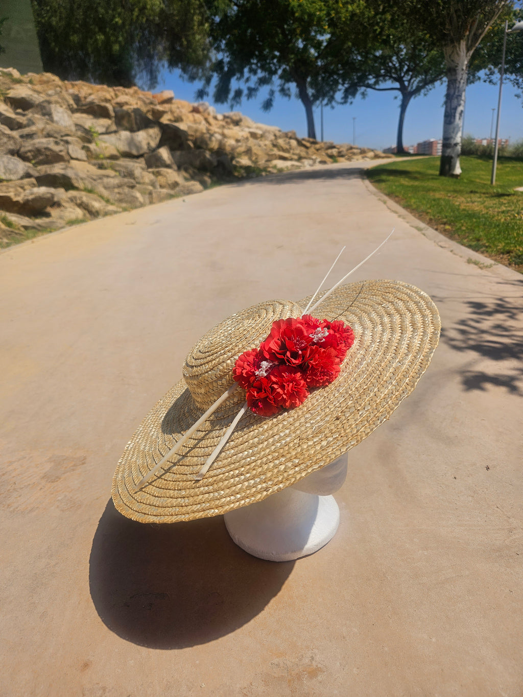 Pamela de paja de ala ancha con flor roja y detalle de lazo trasero