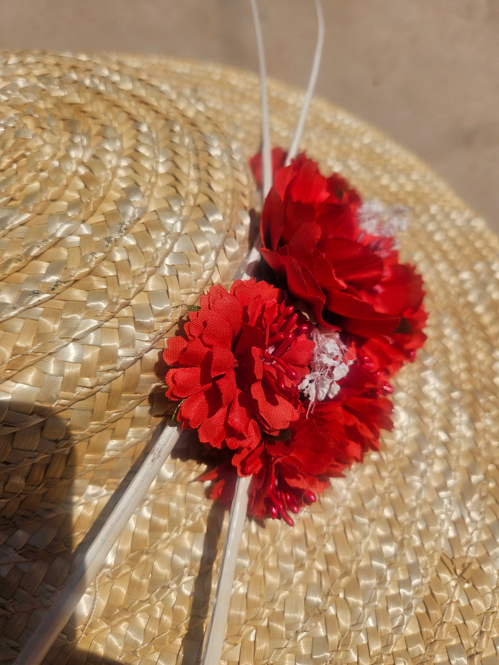 Pamela de paja con flores rojas y cintas blancas entrelazadas