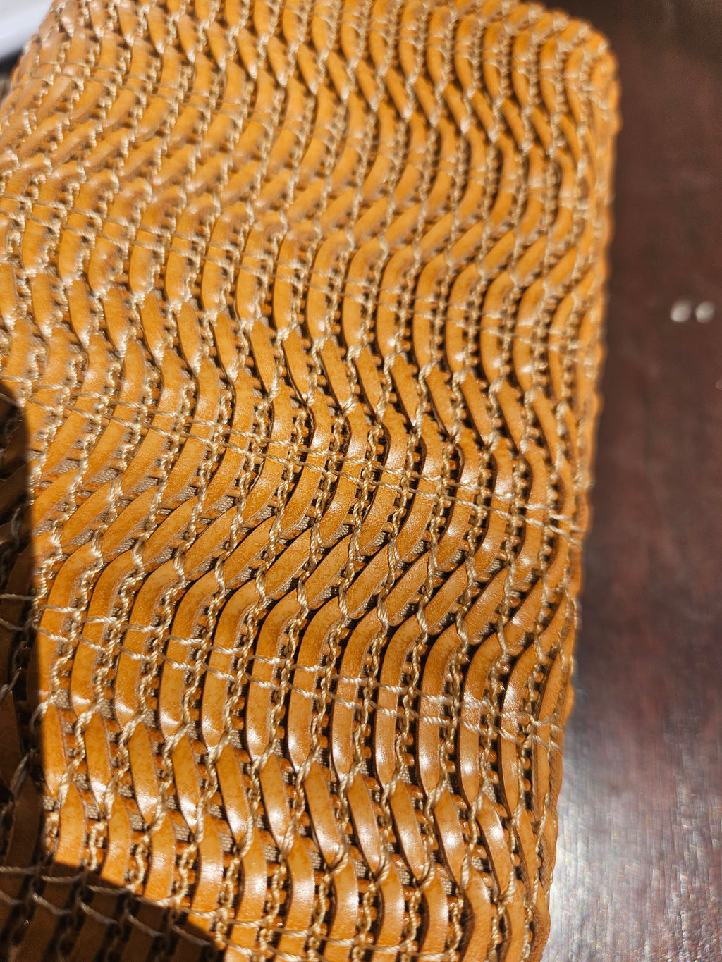 Detalle del tejido del bolso de rafia camel en patrón de ondas y anillos