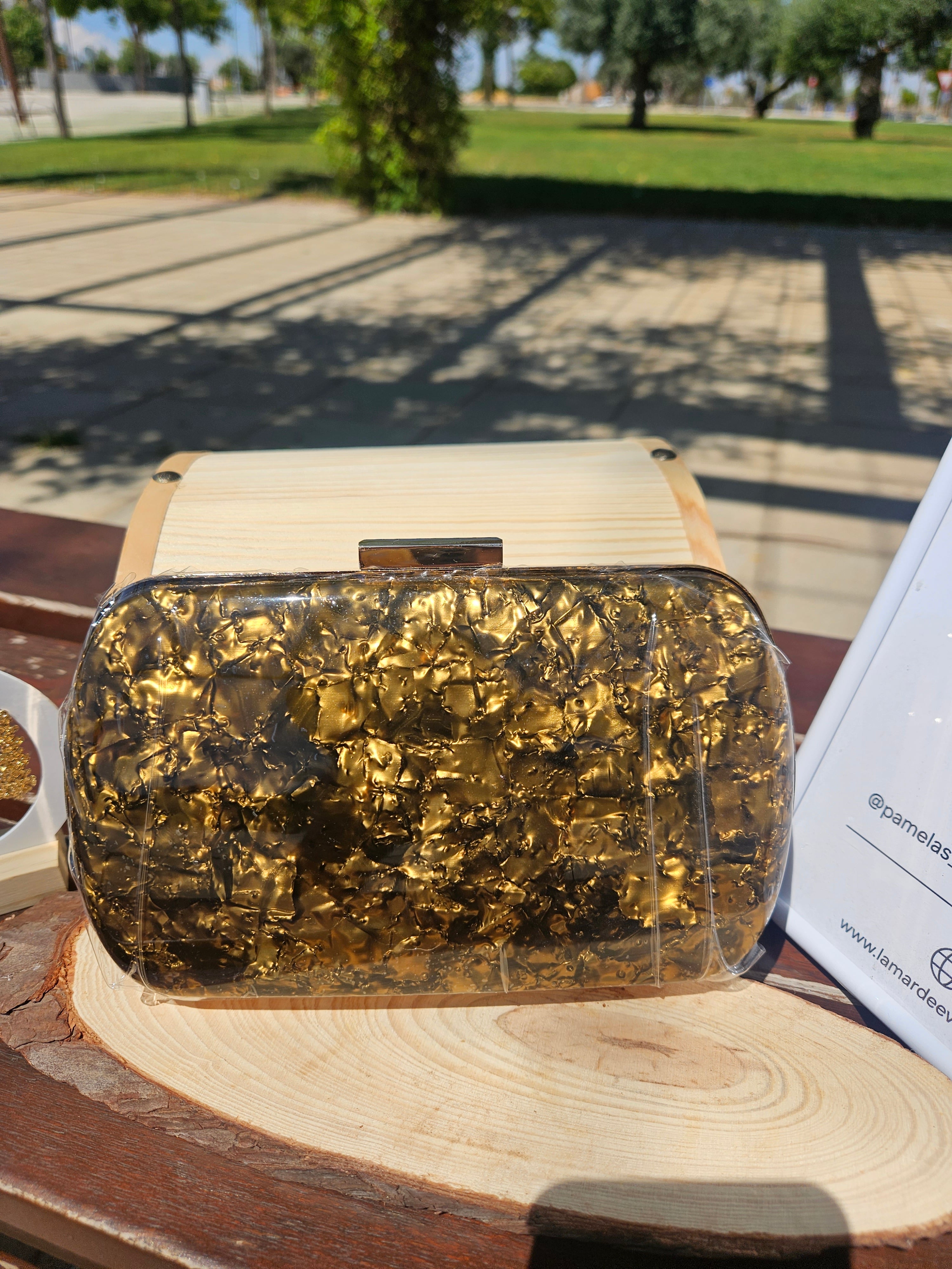 Bolso NY con asa corta y cierre rectangular; exterior dorado texturizado