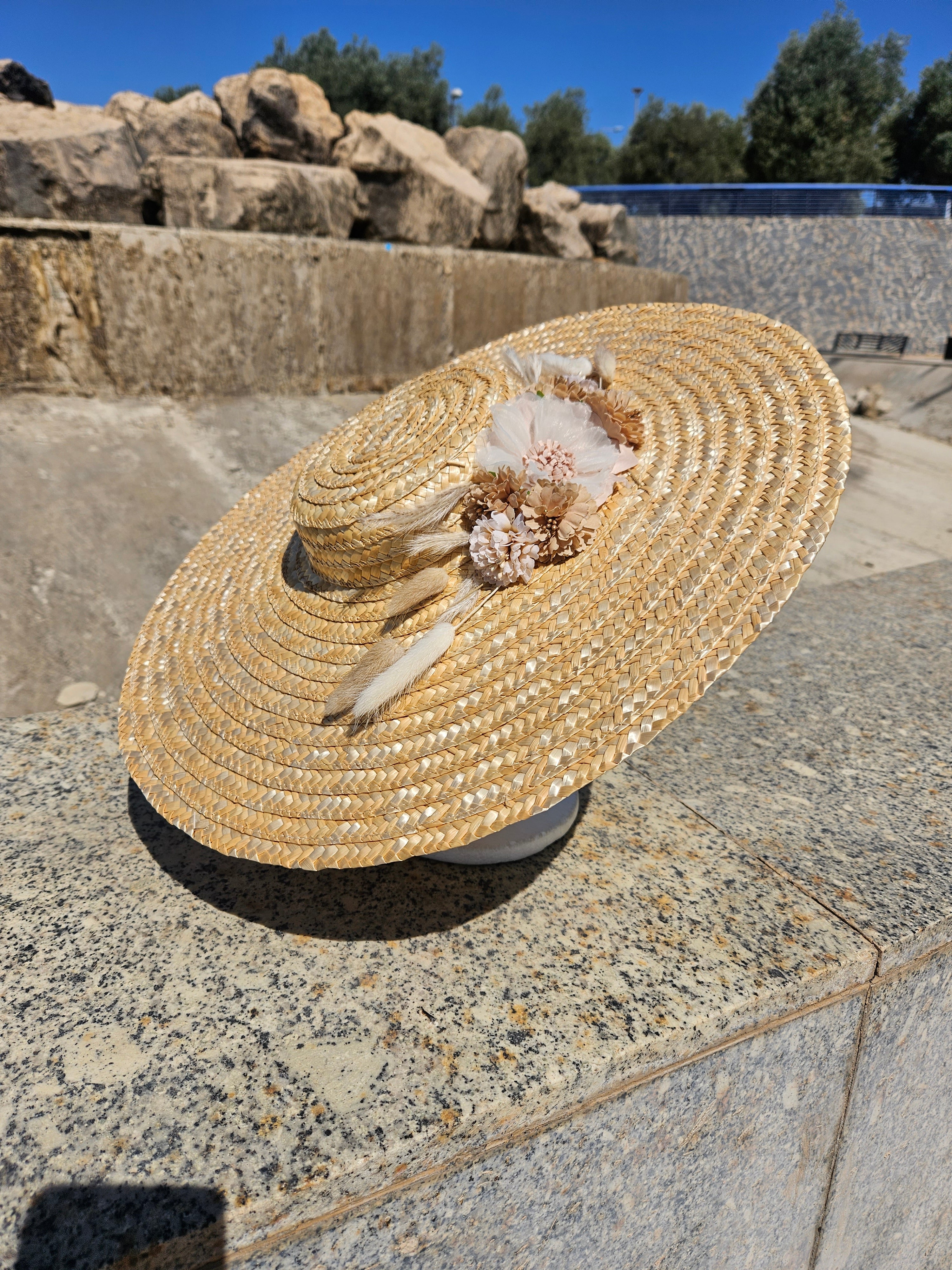Sombrero de paja ancho con adorno floral beige y lazos blancos en el lateral