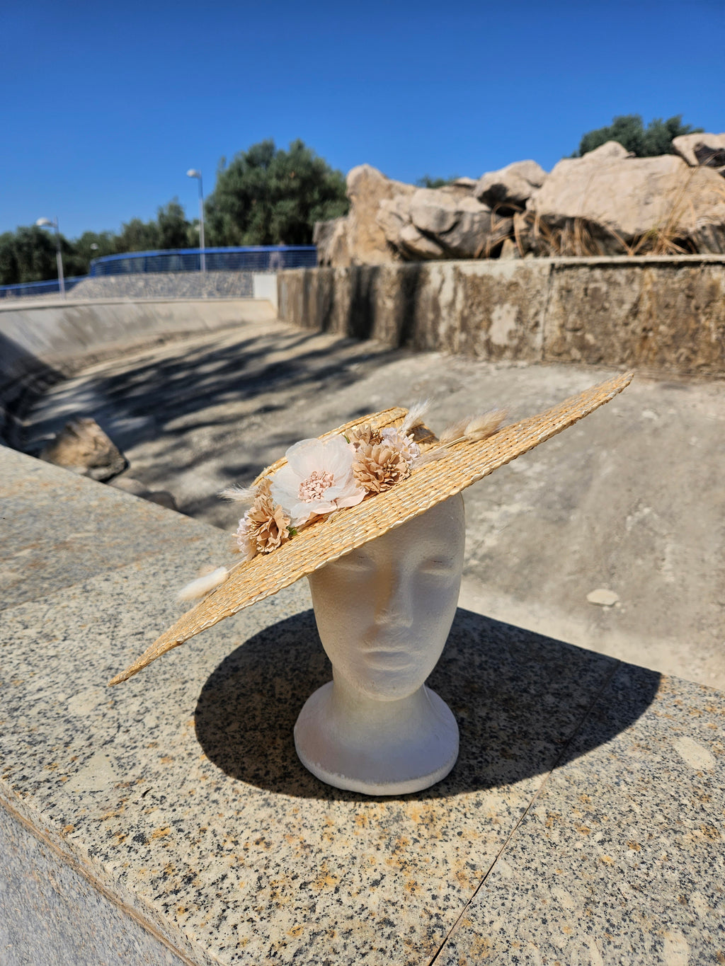 Sombrero de paja con ala grande, adorno floral beige y cinta blanca en el borde