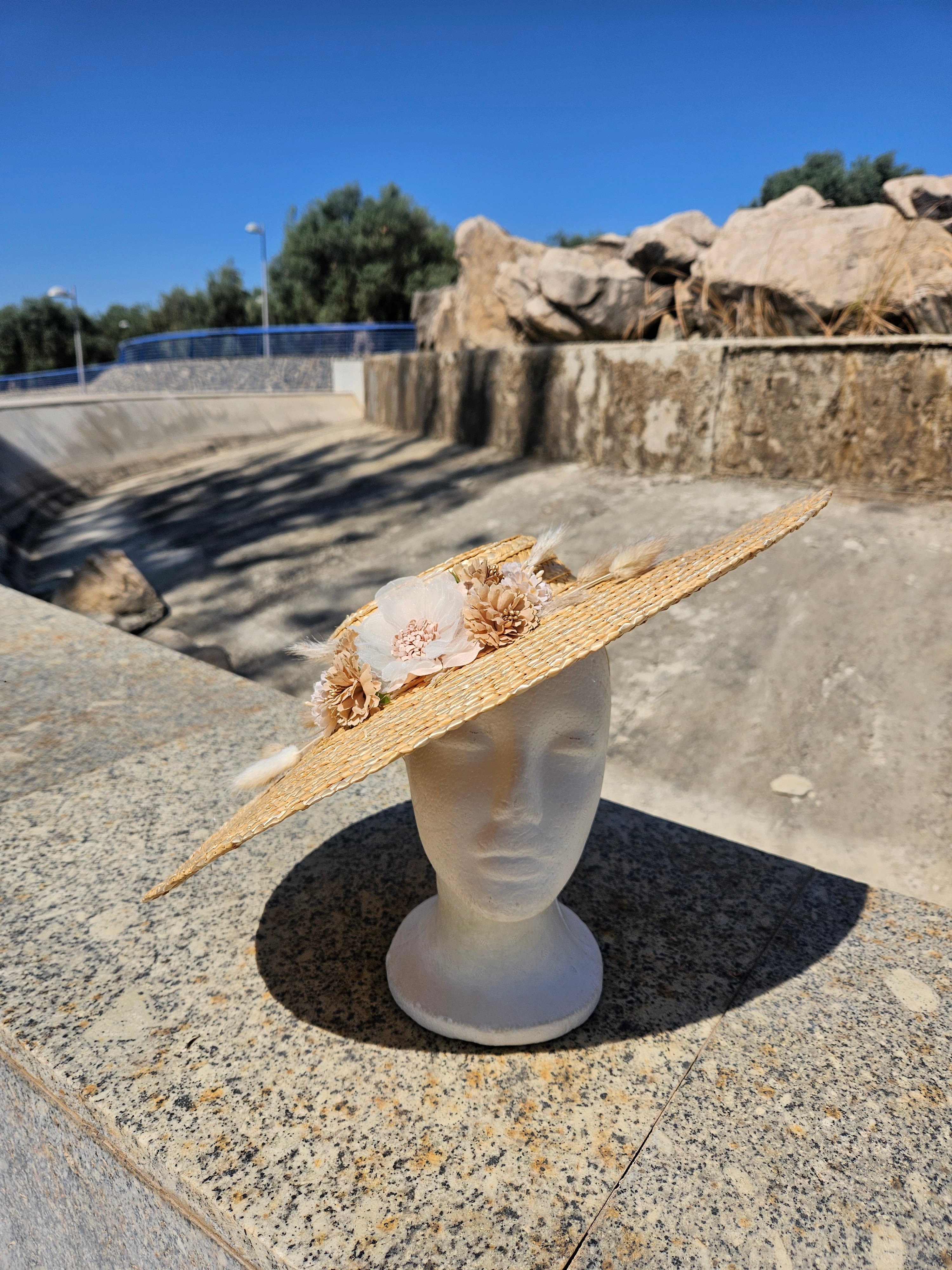 Sombrero de paja con ala grande, adorno floral beige y cinta blanca en el borde