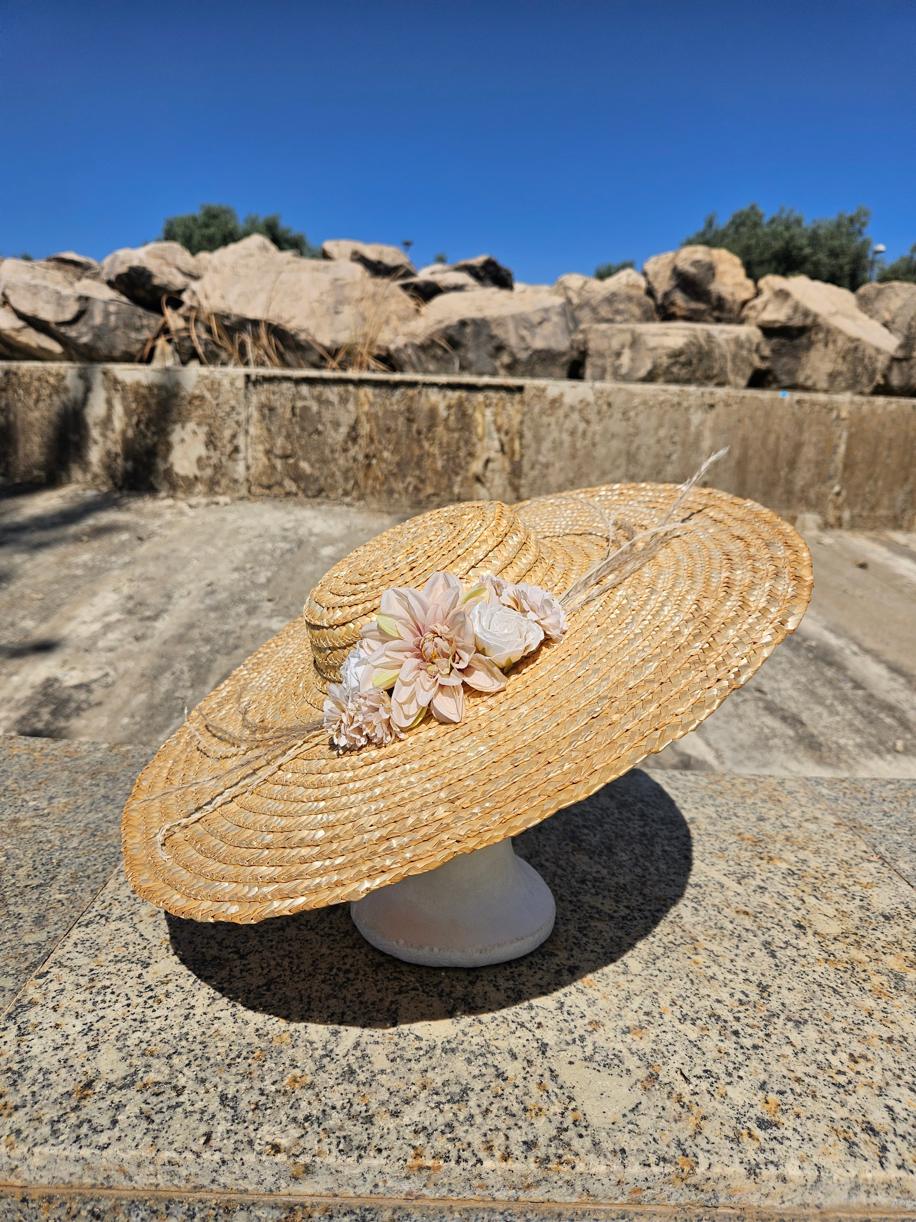 Sombrero de paja beige con flor rosa, ala amplia y espiral trenzada
