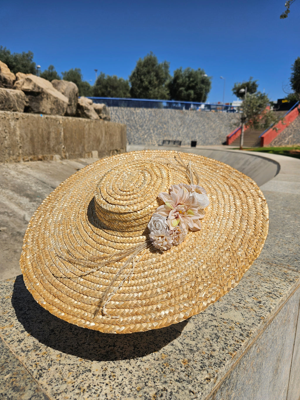 Sombrero de paja beige con flor rosa sobre copa trenzada en espiral