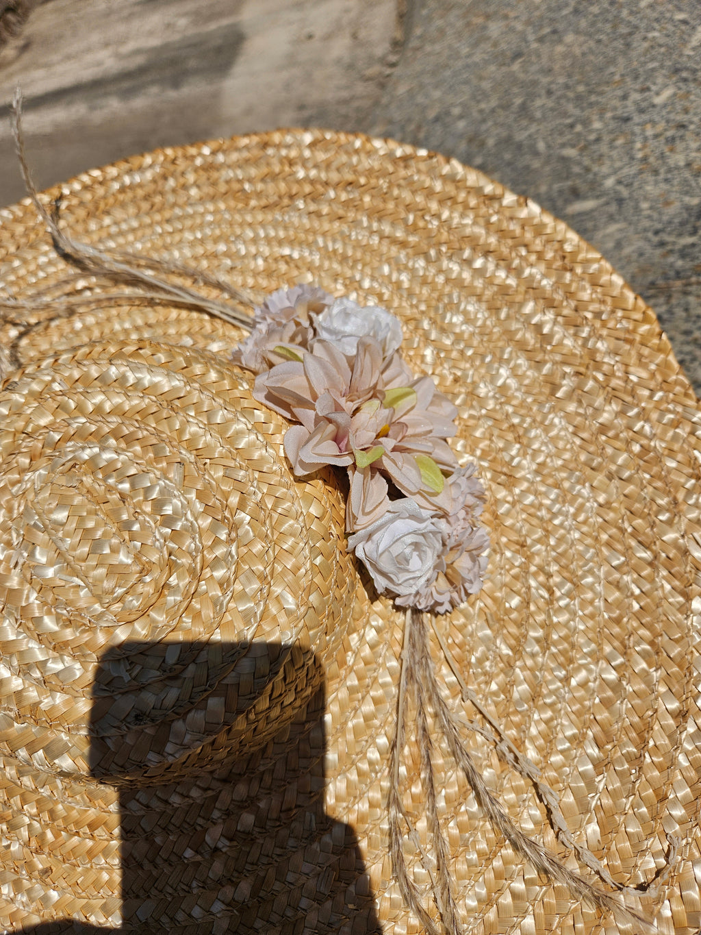 Sombrero de paja beige con flores blancas y rosadas en la copa, detalle trenzado