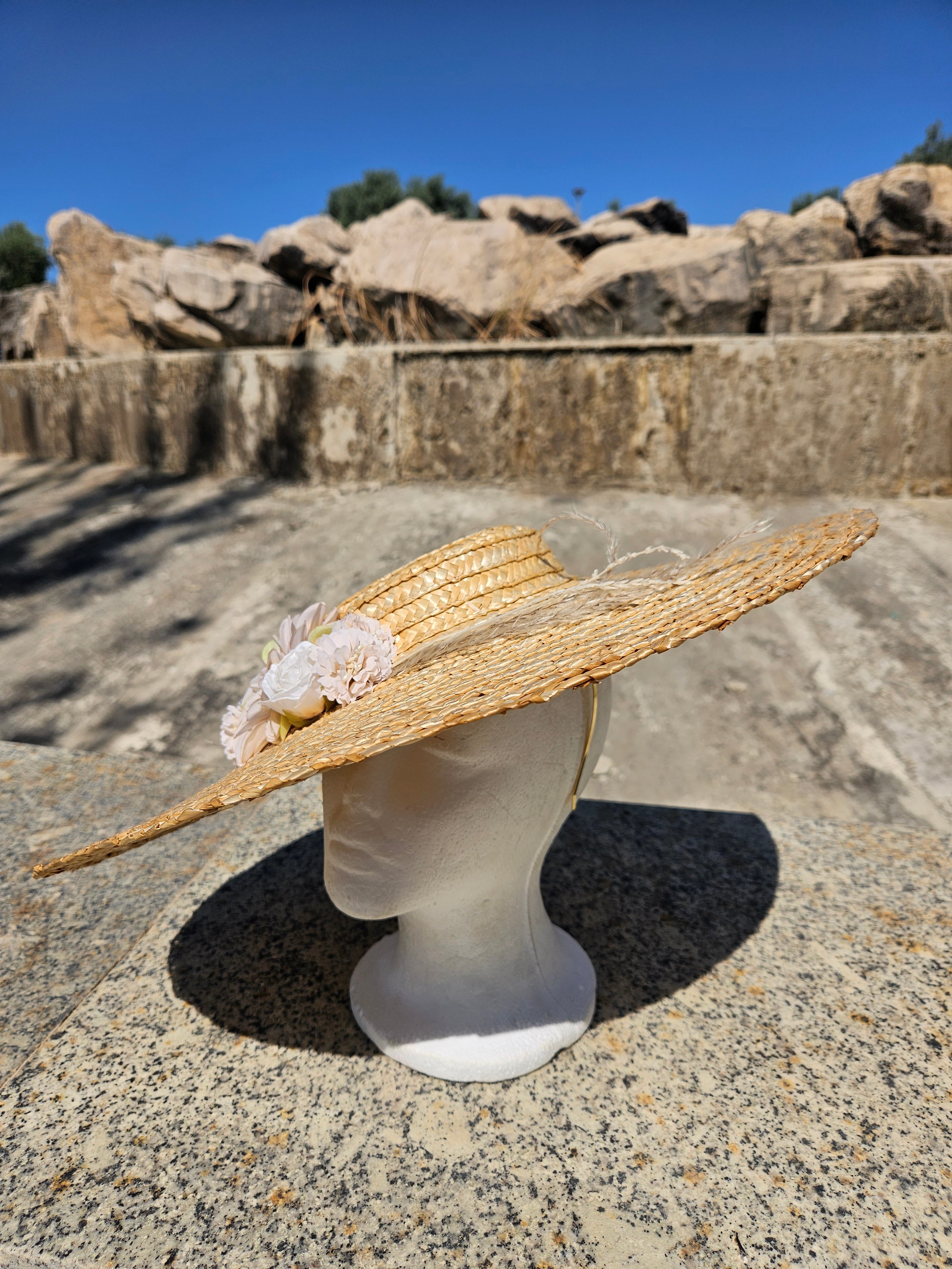 Sombrero de paja beige con flor rosa y ala ligeramente levantada, vista lateral