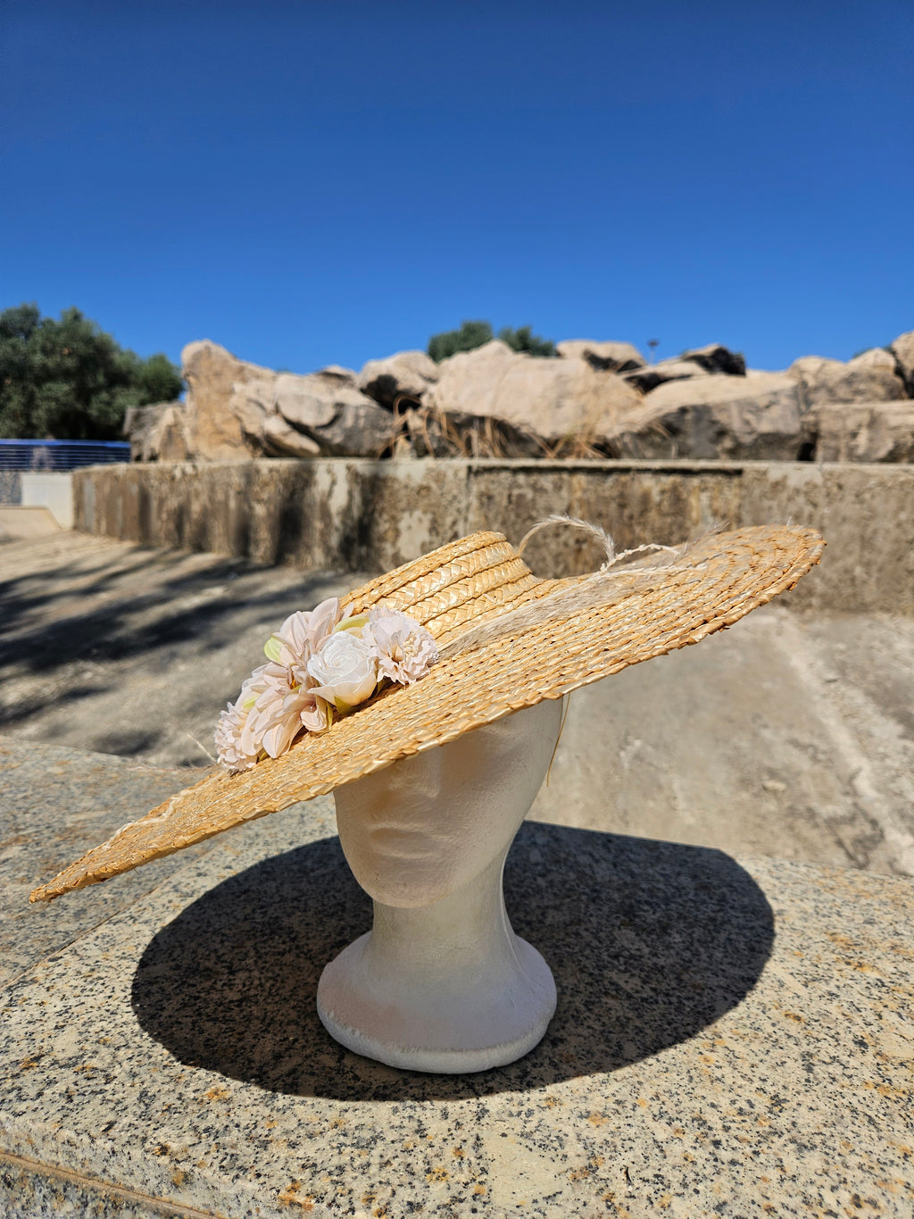 Sombrero de paja beige con flor rosa, ala amplia y trenzado en espiral