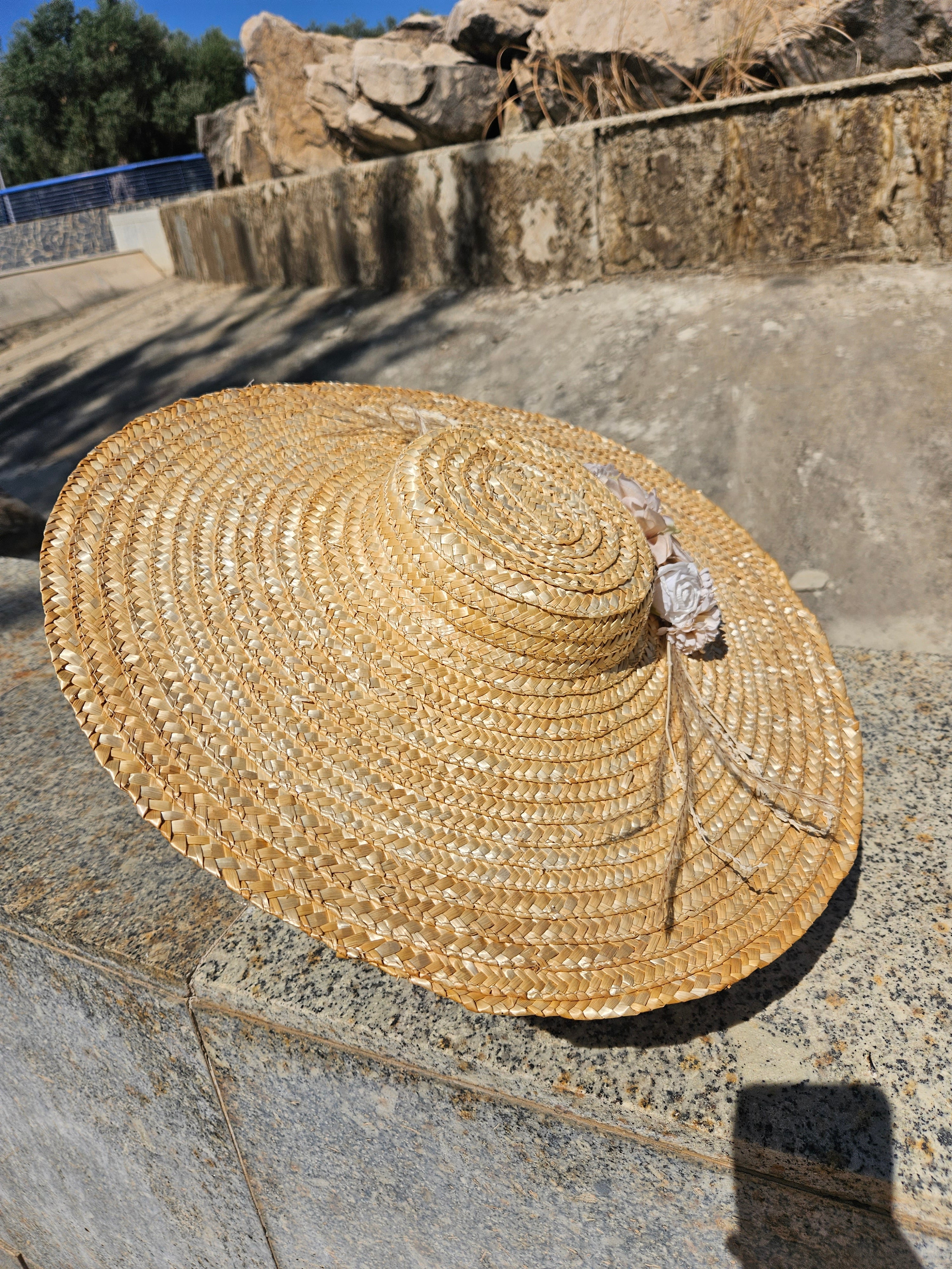 Sombrero de paja beige con flor rosa en la copa y trenzado circular, ala amplia