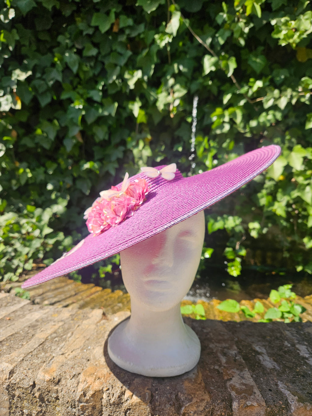 Pamela fucsia de ala ancha con ramillete de flores rosas sobre maniquí