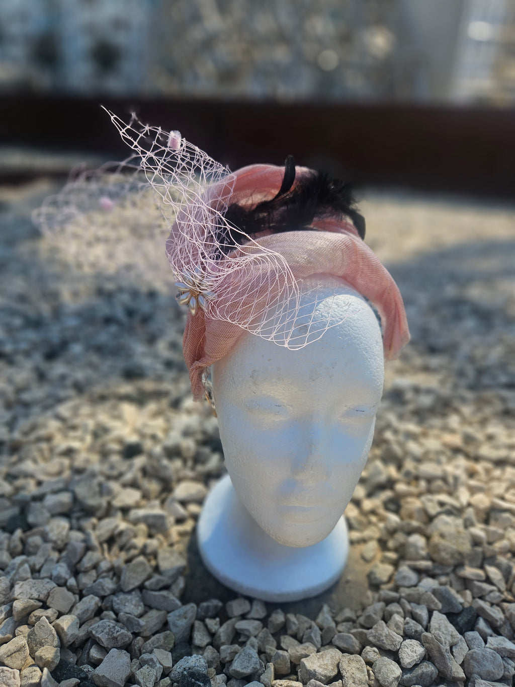 tocado Nandama rosa empolvado con velo de tul y pluma negra