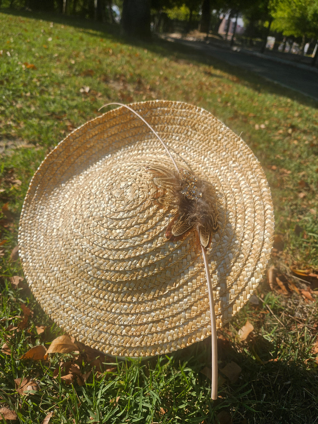 Sombrero tipo pamela de rafia beige con tocado floral y plumas en la parte frontal