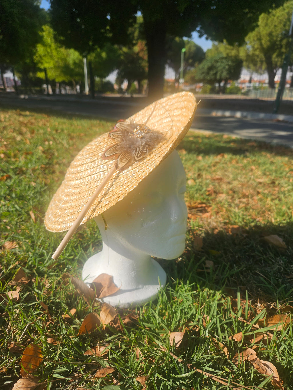 Sombrero tipo pamela beige de ala ancha con adorno frontal, sobre maniquí