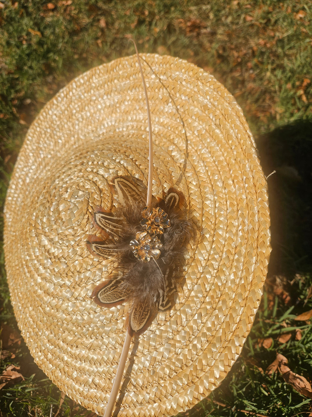 Sombrero tipo pamela beige con tocado central de flor y plumas, vista superior