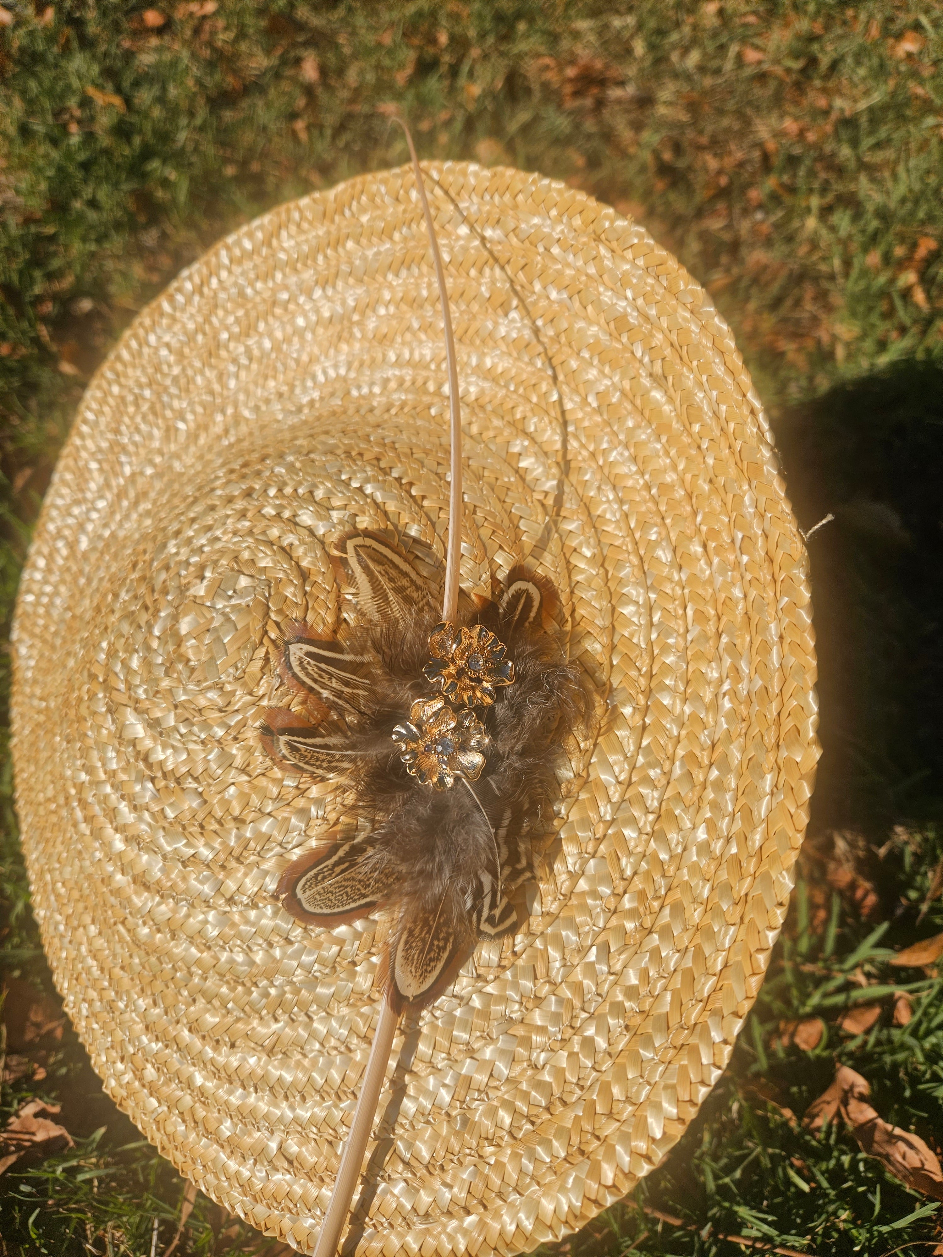 Sombrero tipo pamela beige con tocado central de flor y plumas, vista superior