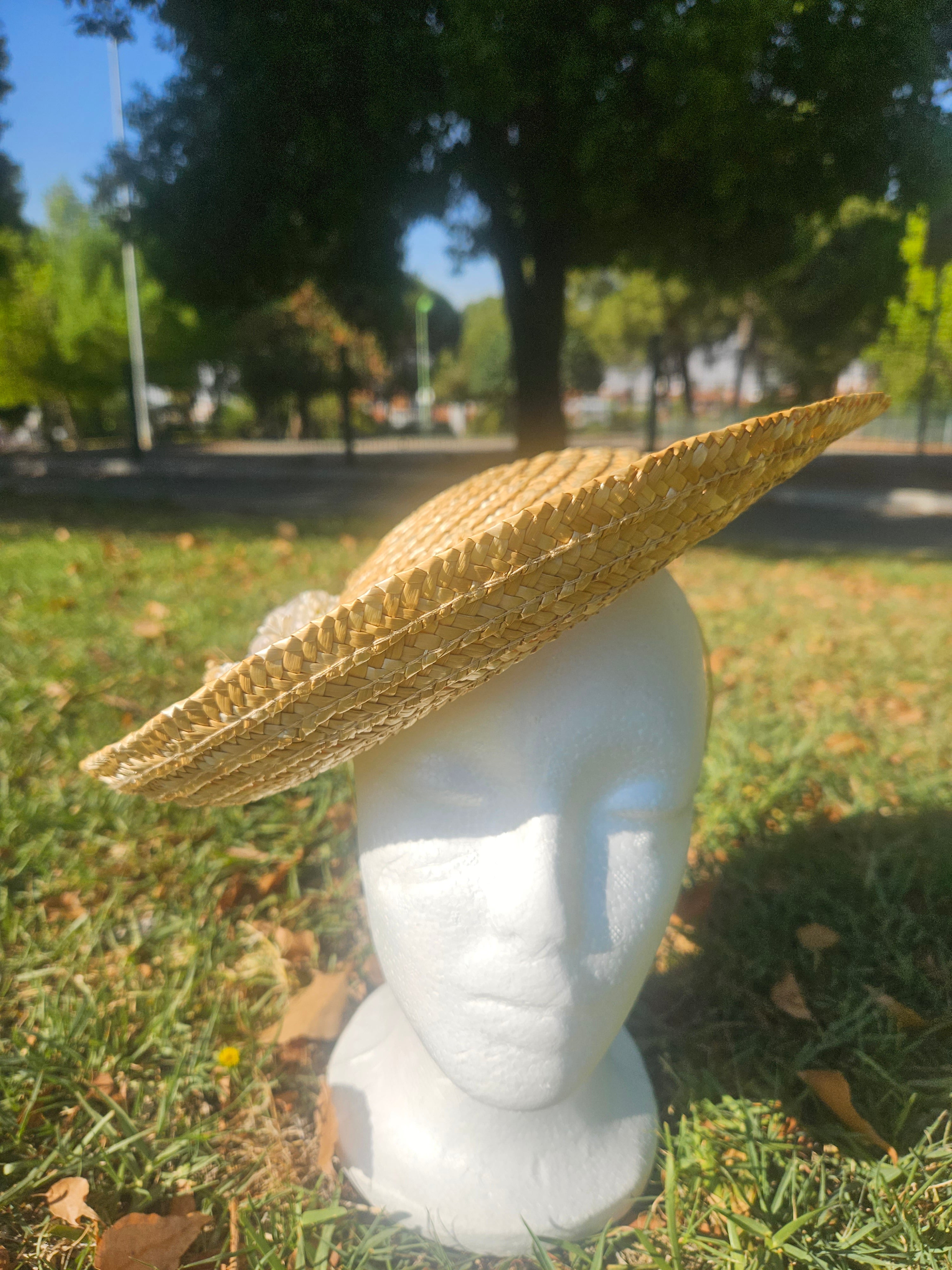 Sombrero de paja de ala ancha color beige con flores blancas en el lateral