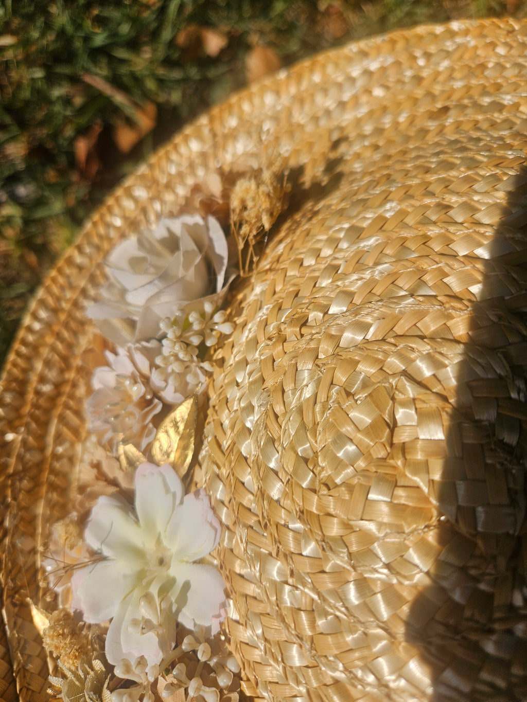 Detalle de pamela de paja beige con flores blancas y relieve tejido