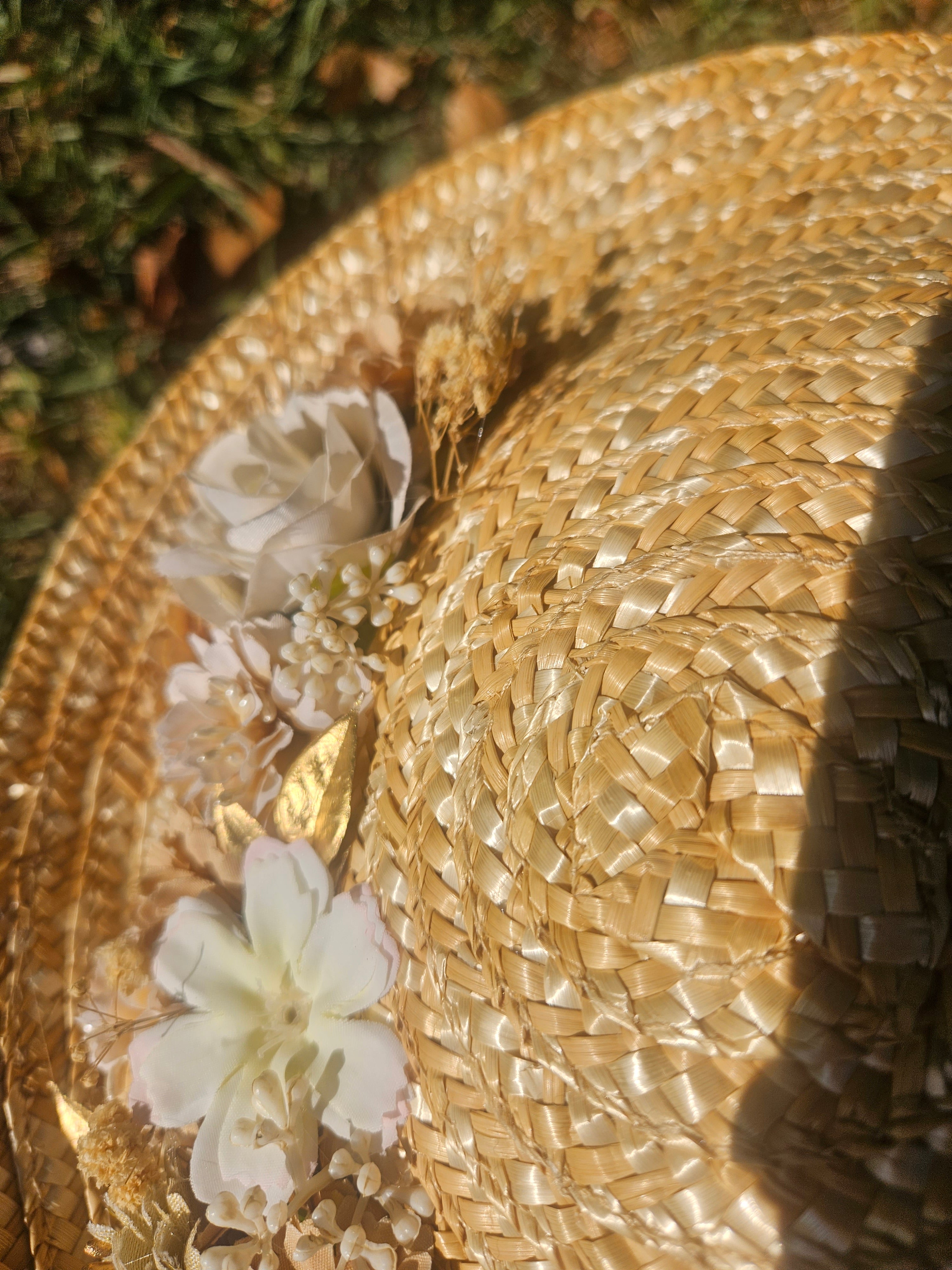 Detalle de pamela de paja beige con flores blancas y relieve tejido