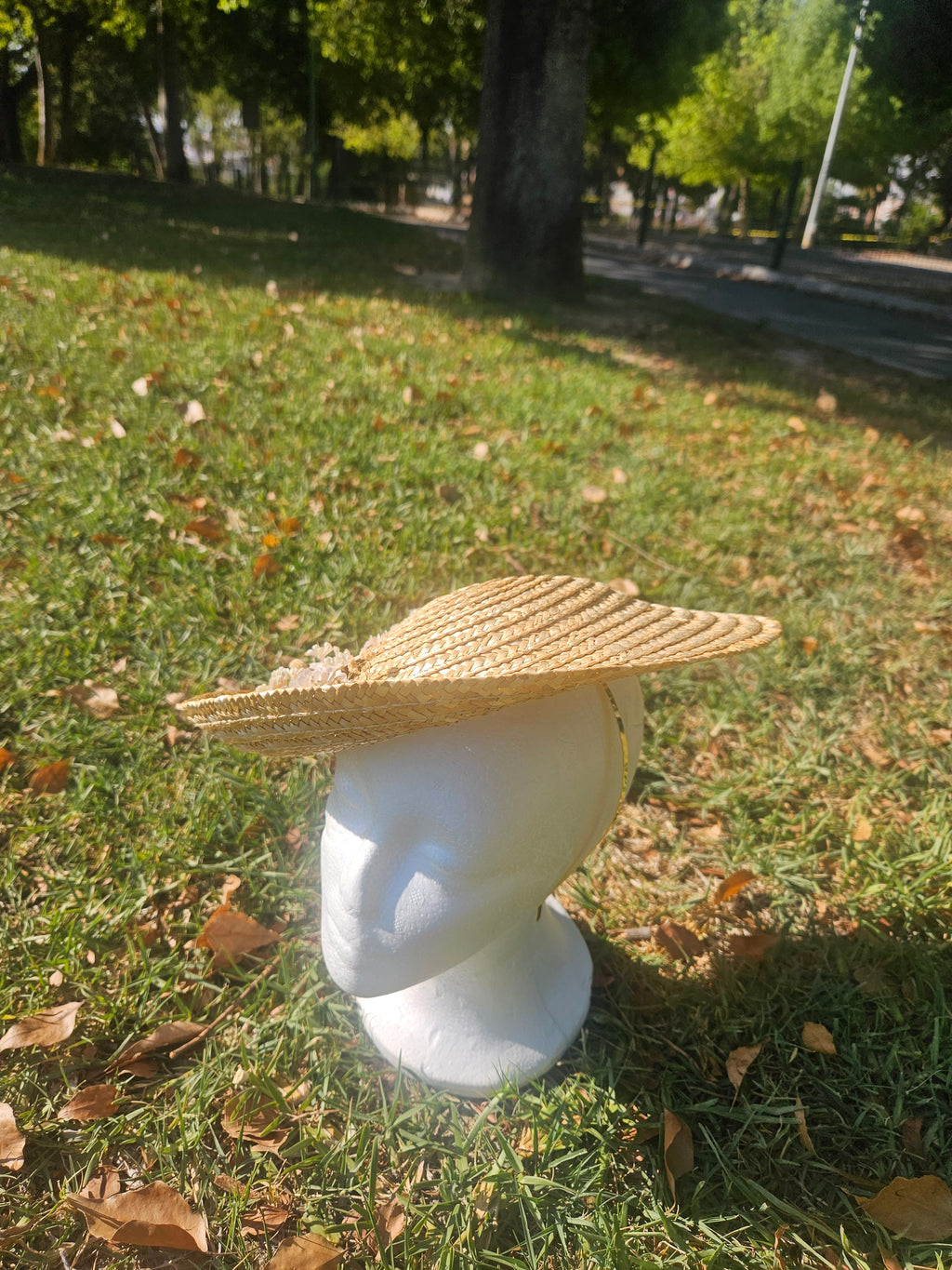 Sombrero de paja beige de ala ancha sobre cabeza blanca con flores blancas