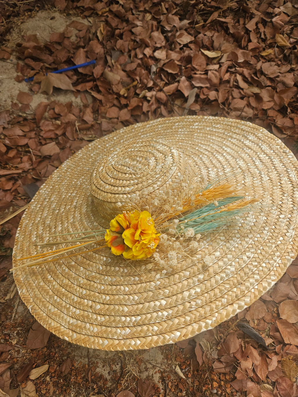 Sombrero de paja beige de ala ancha con flor amarilla y plumitas turquesa