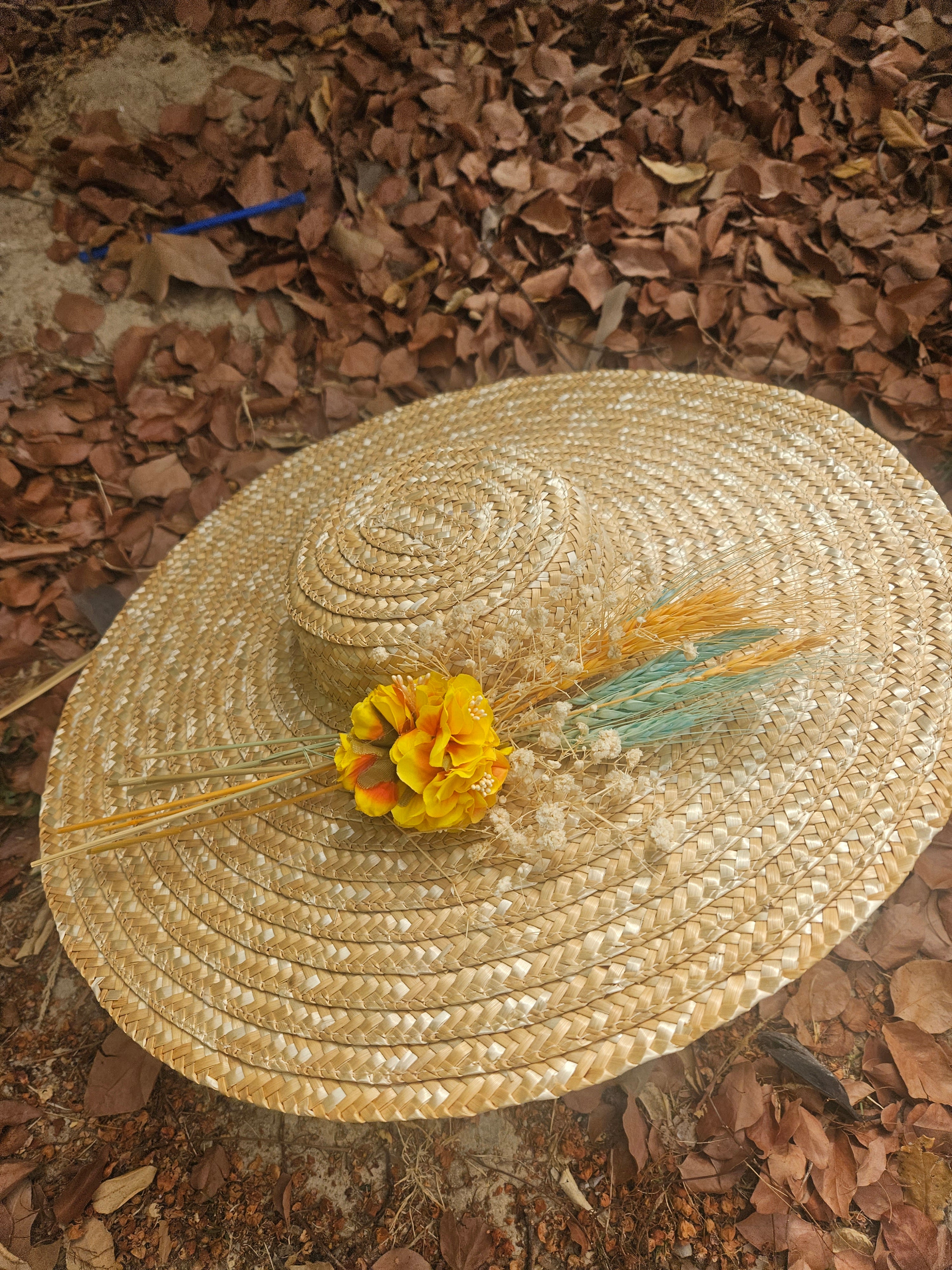 Sombrero de paja beige de ala ancha con flor amarilla y plumitas turquesa