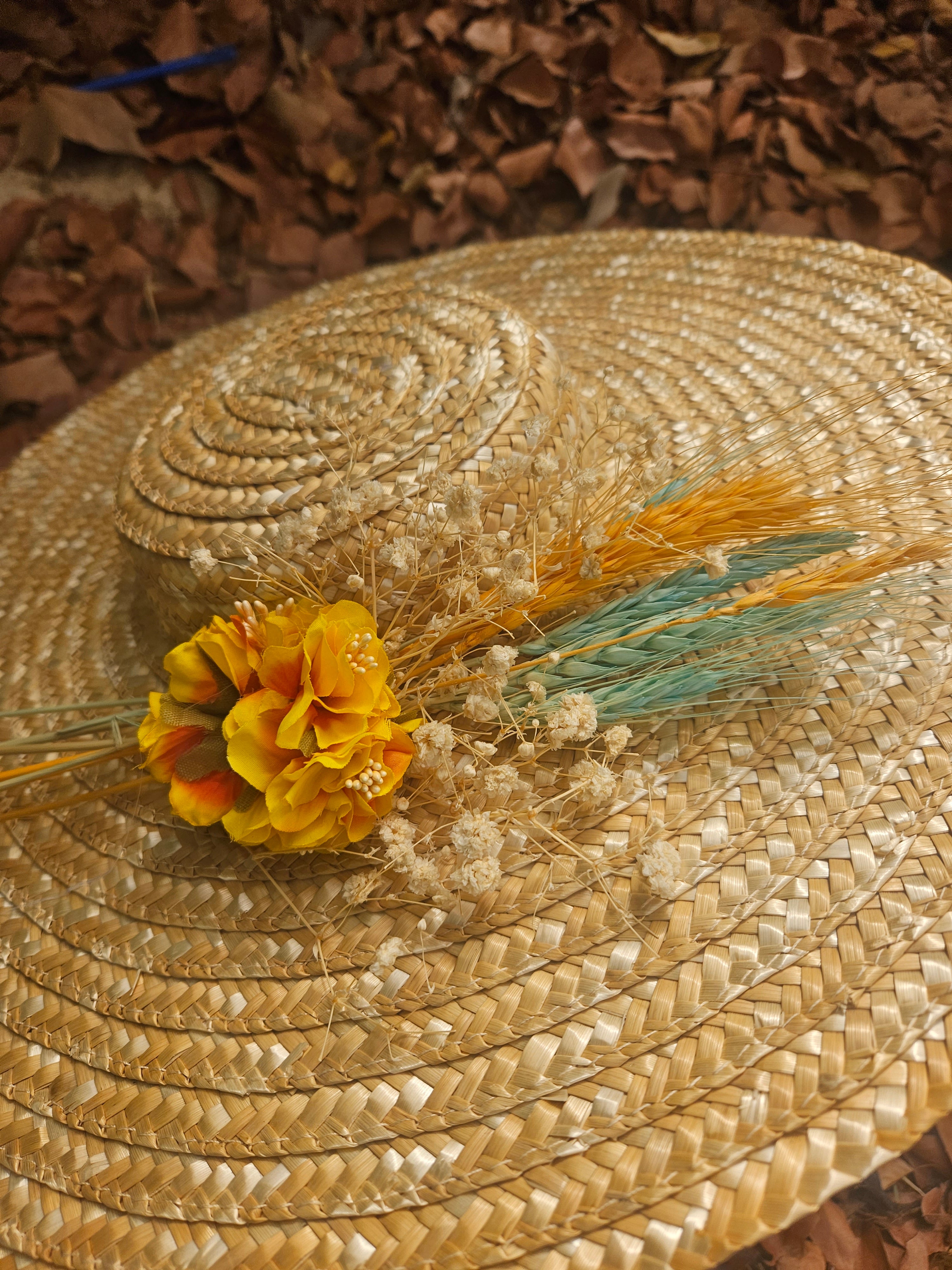 Sombrero de paja beige con flor amarilla y detalles de plumas turquesa en primer plano