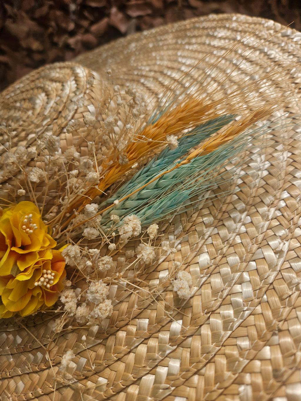Sombrero de paja beige con flor amarilla y ramitas decorativas turquesa