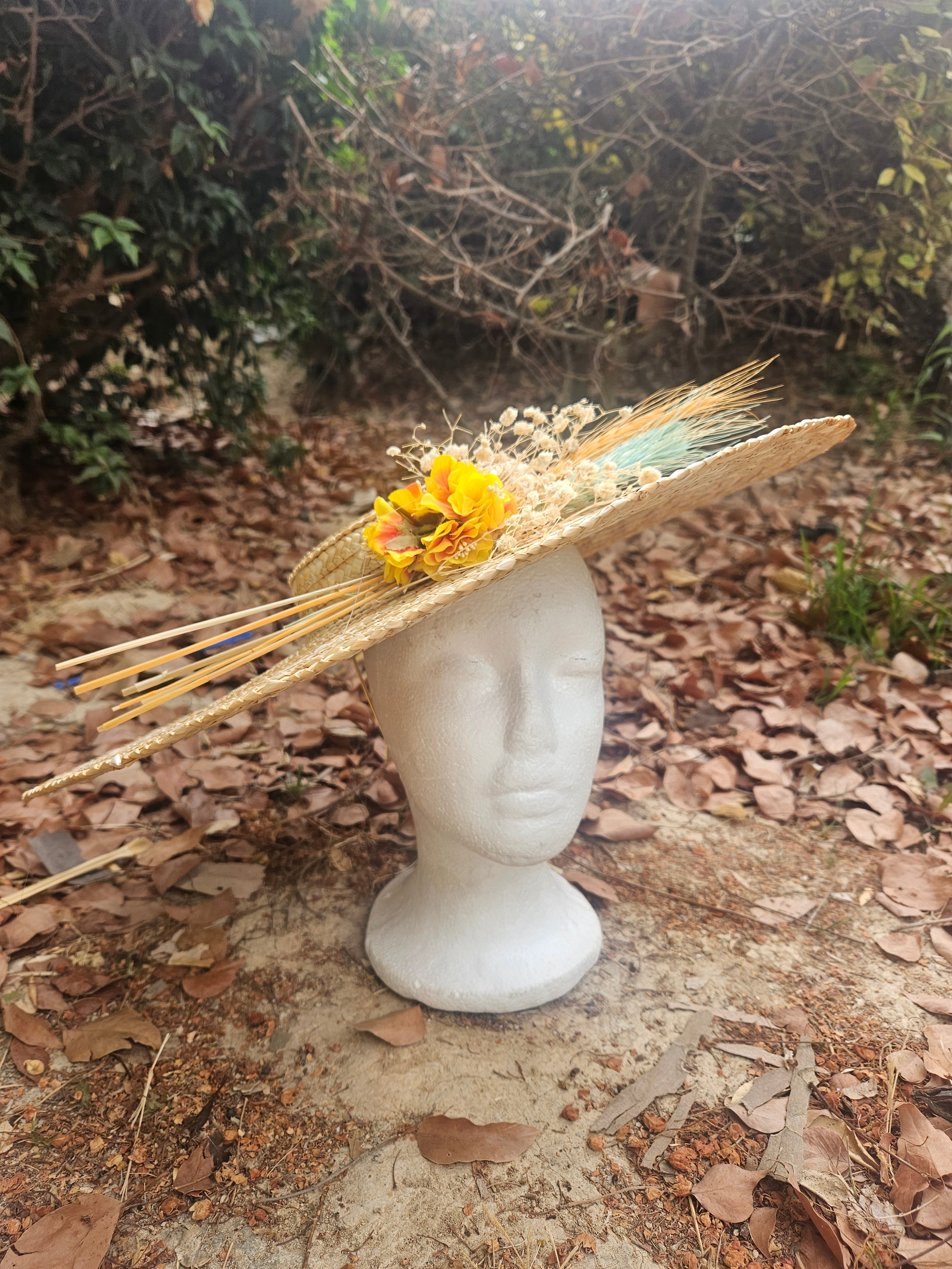 Sombrero de paja beige con flor amarilla y cintas turquesa, sobre maniquí blanco