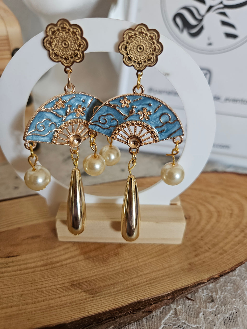 Pendientes dorados con colgantes: abanicos azules con detalles dorados y perlas.