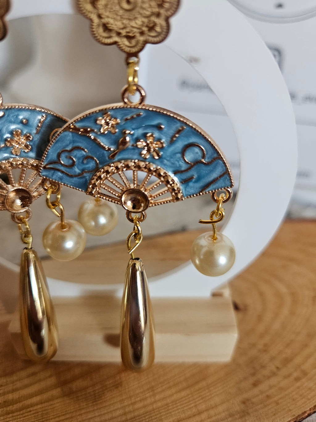Pendientes largos dorados: círculo azul con abanico, colgantes con perlas y esfera.
