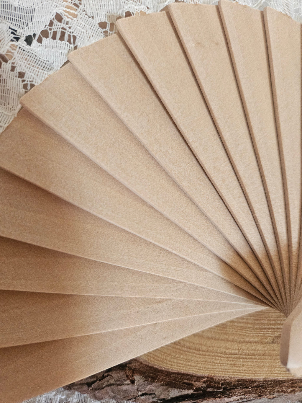 Abanico de madera beige, desplegado, con varillas y borde tipo volante