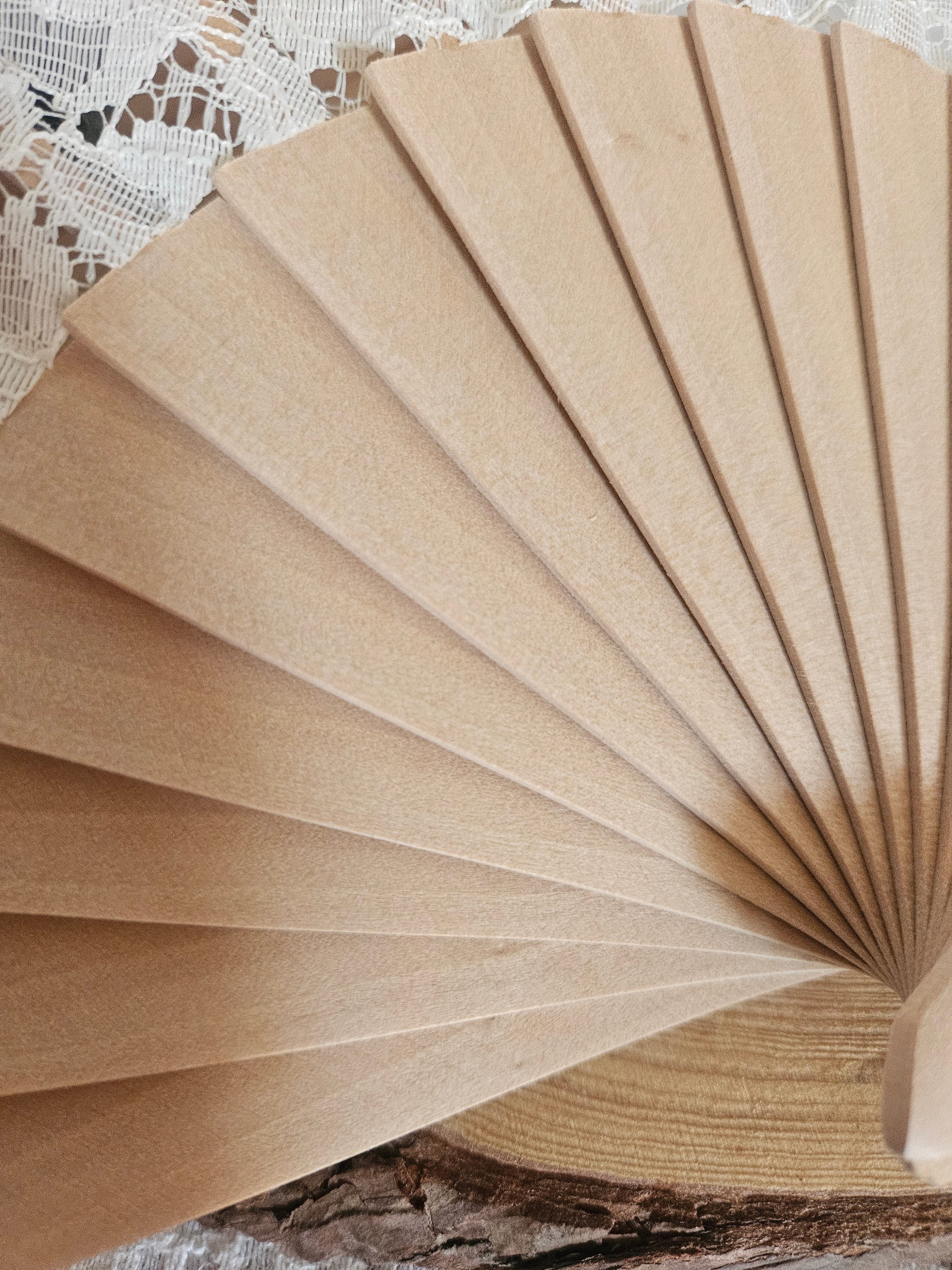 Abanico de madera beige, desplegado, con varillas y borde tipo volante