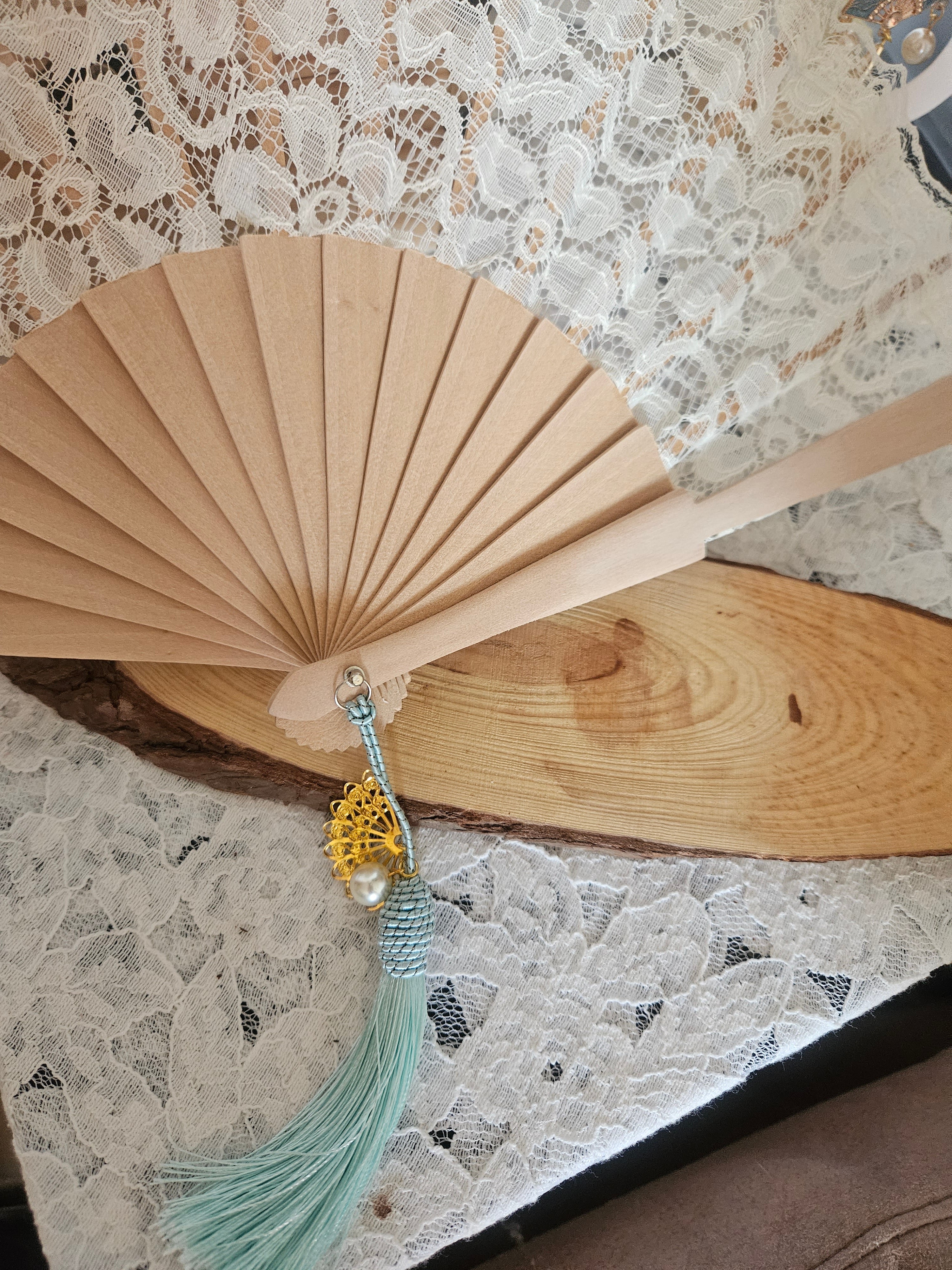Abanico beige con borla turquesa y adorno dorado floral; punto de unión plateado