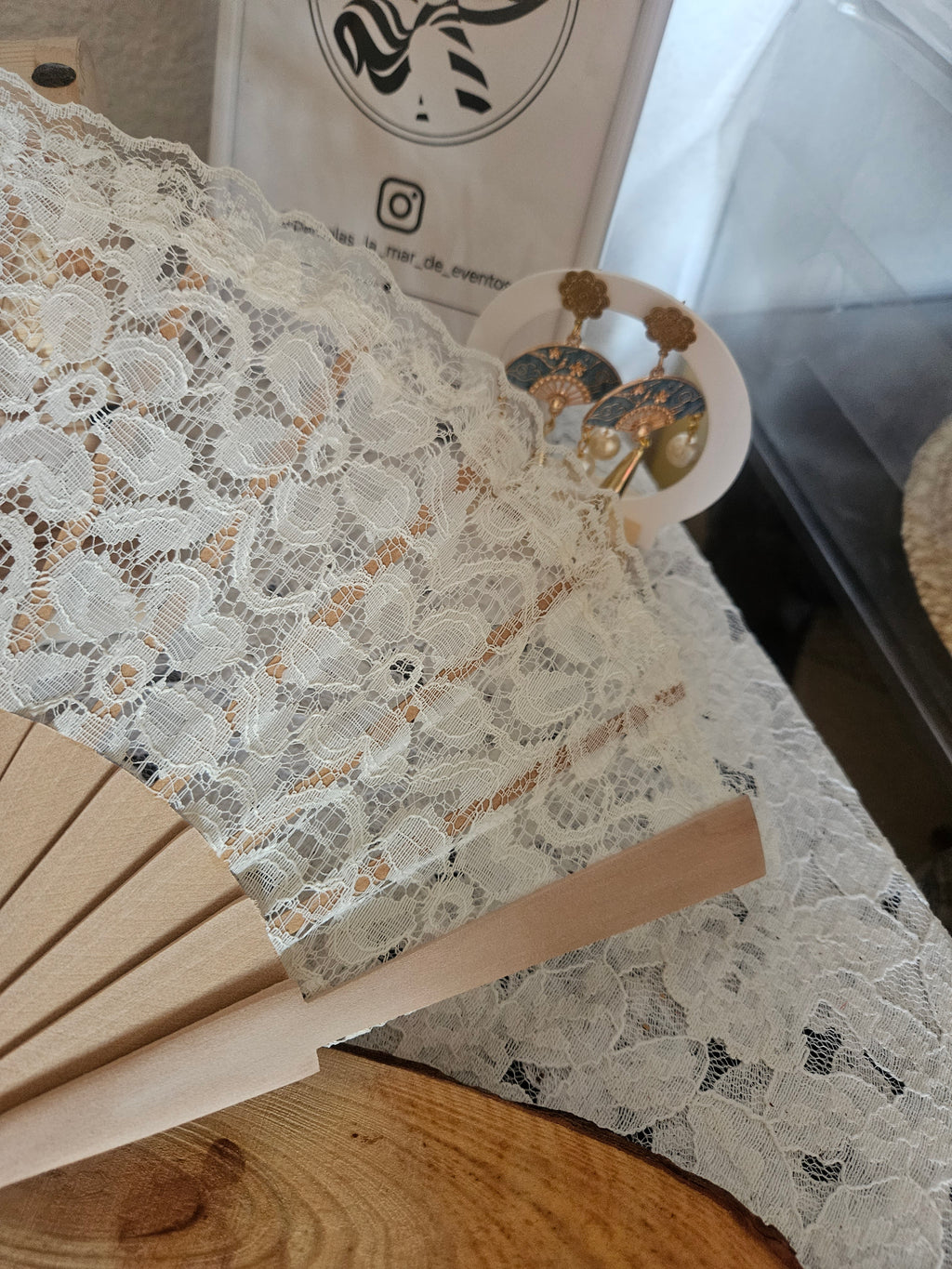 Abanico de encaje blanco sobre varillas beige; borla y tiras decorativas fuera de foco