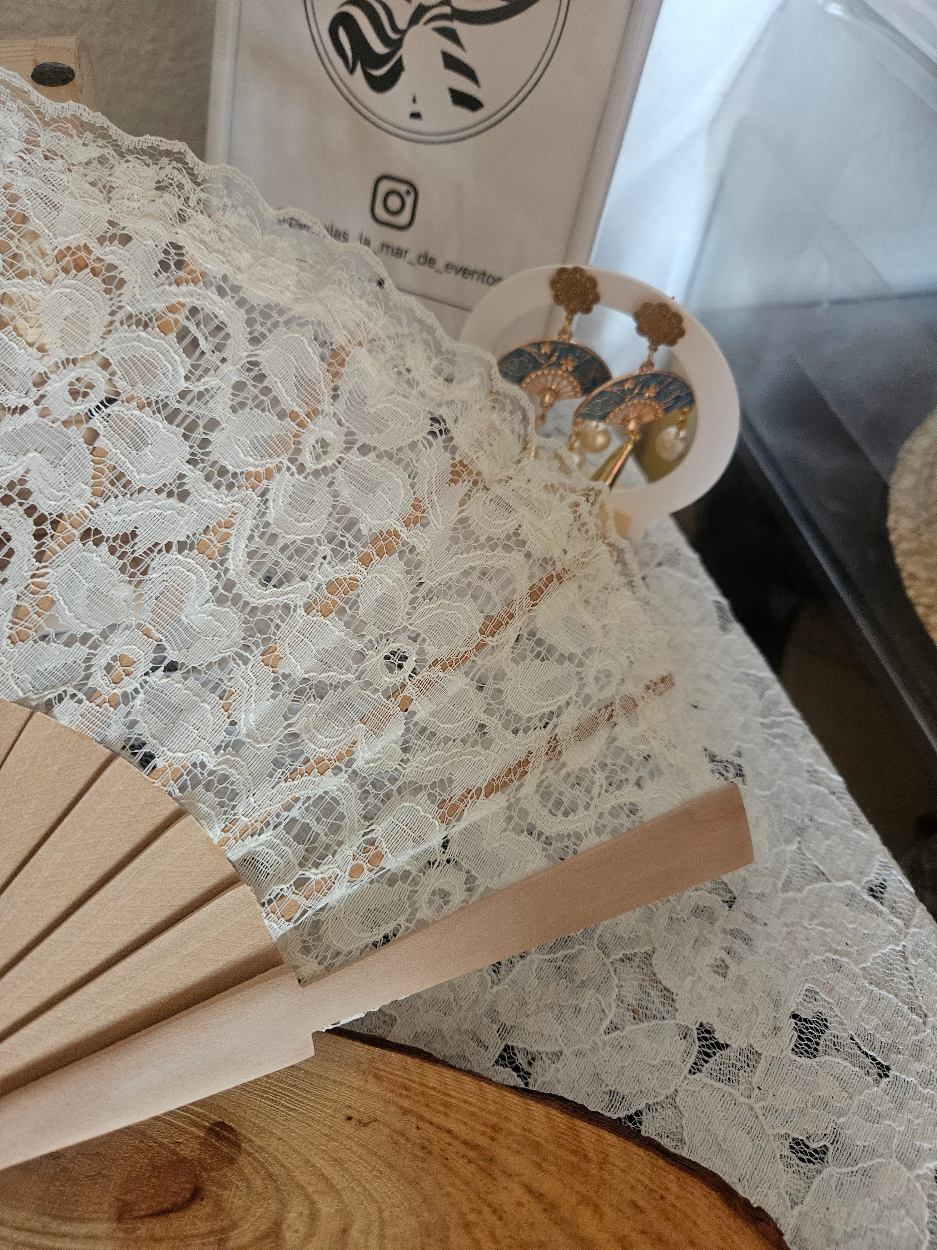 Abanico de encaje blanco sobre varillas beige; borla y tiras decorativas fuera de foco