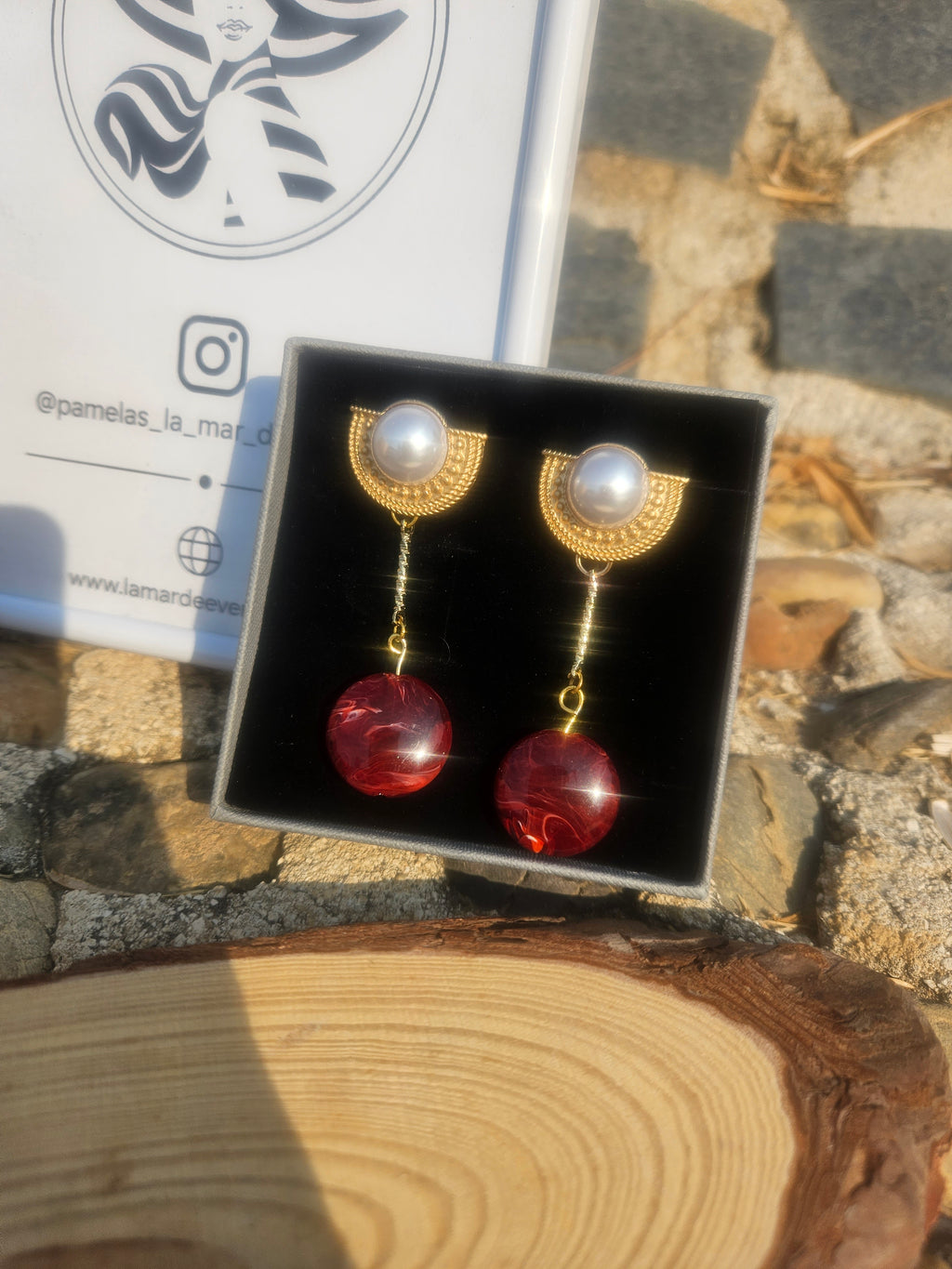 Pendientes colgantes: perla blanca, gotas rojas y cadena dorada en caja negra.