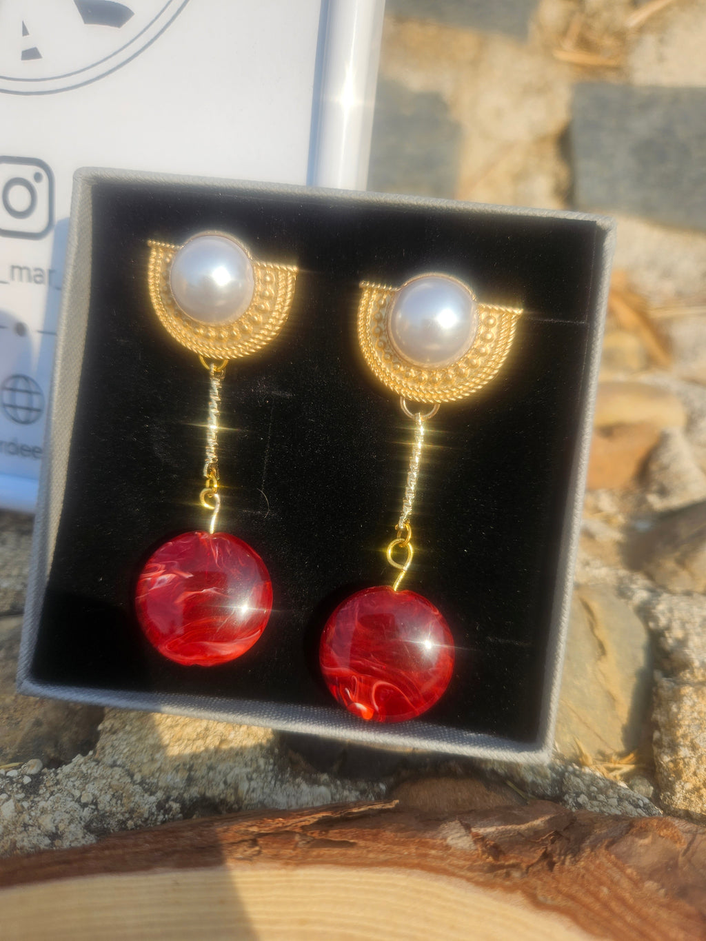 Pendientes colgantes con perla blanca y dos gotas rojas, acabado dorado.