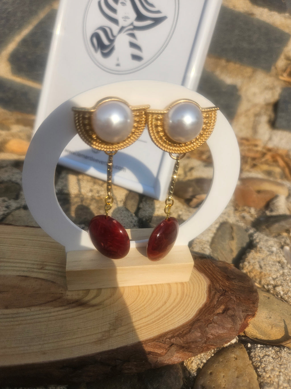 Pendientes de perla blanca con dos gotas rojas colgantes y baño dorado.