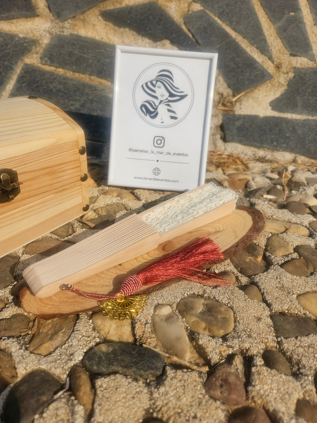 Abanico de madera con borla granate y soporte, visto con caja de empaque